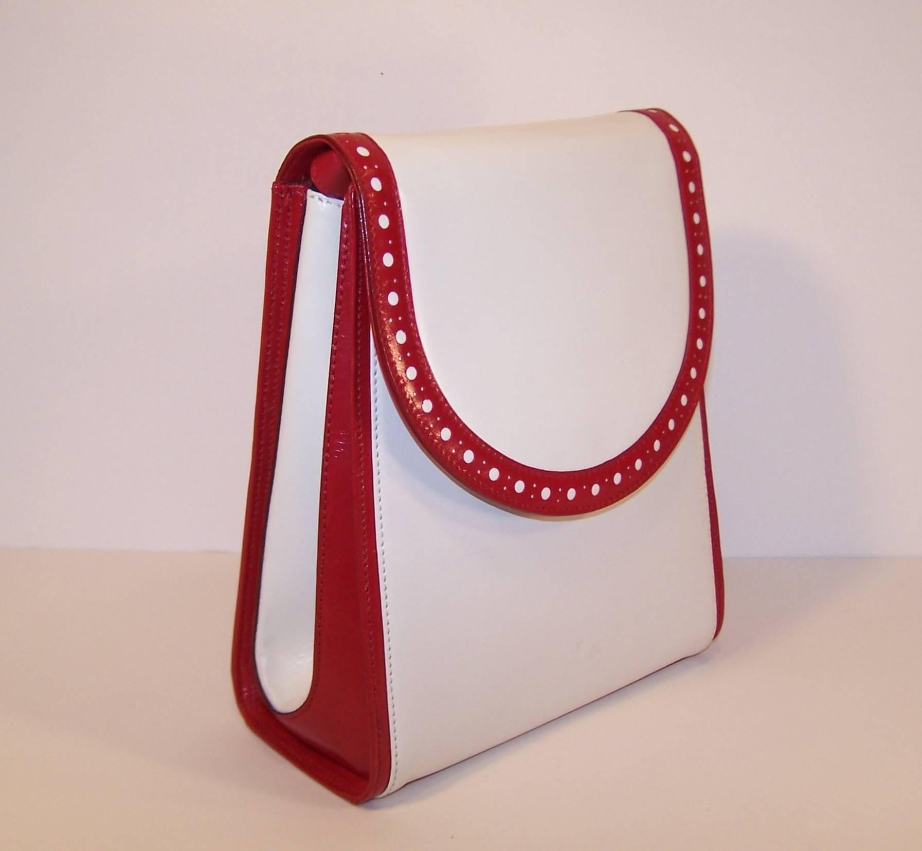 Bruno Magli has been producing quality Italian leather goods since 1936.  This spectator style handbag is designed with beautiful cherry red leather brightened with white leather panels at the front and on the sides.  The shoulder strap has three