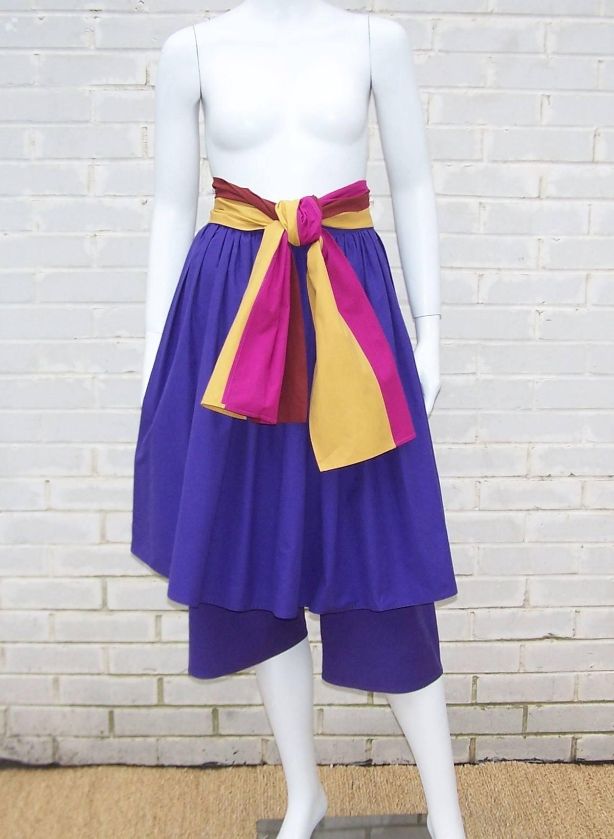 This crisp summery 1970's confection from Gucci combines colorful cotton with a unique silhouette to provide a fun design.  The contrasting color combination of royal purple with a built-in striped sash of goldenrod, fuchsia and burgundy is a