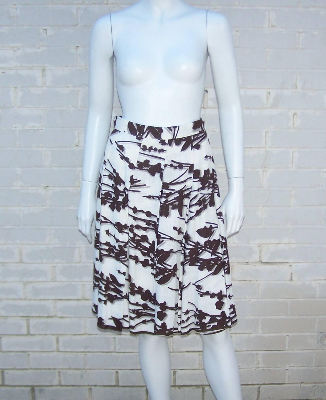 This summery Prada skirt has the look of an open weave linen though it is actually a viscose rayon.  It zips and hooks at the side with top stitched pleating and banding at the hemline.  The unique brown and white abstract flora print has a 3-D op