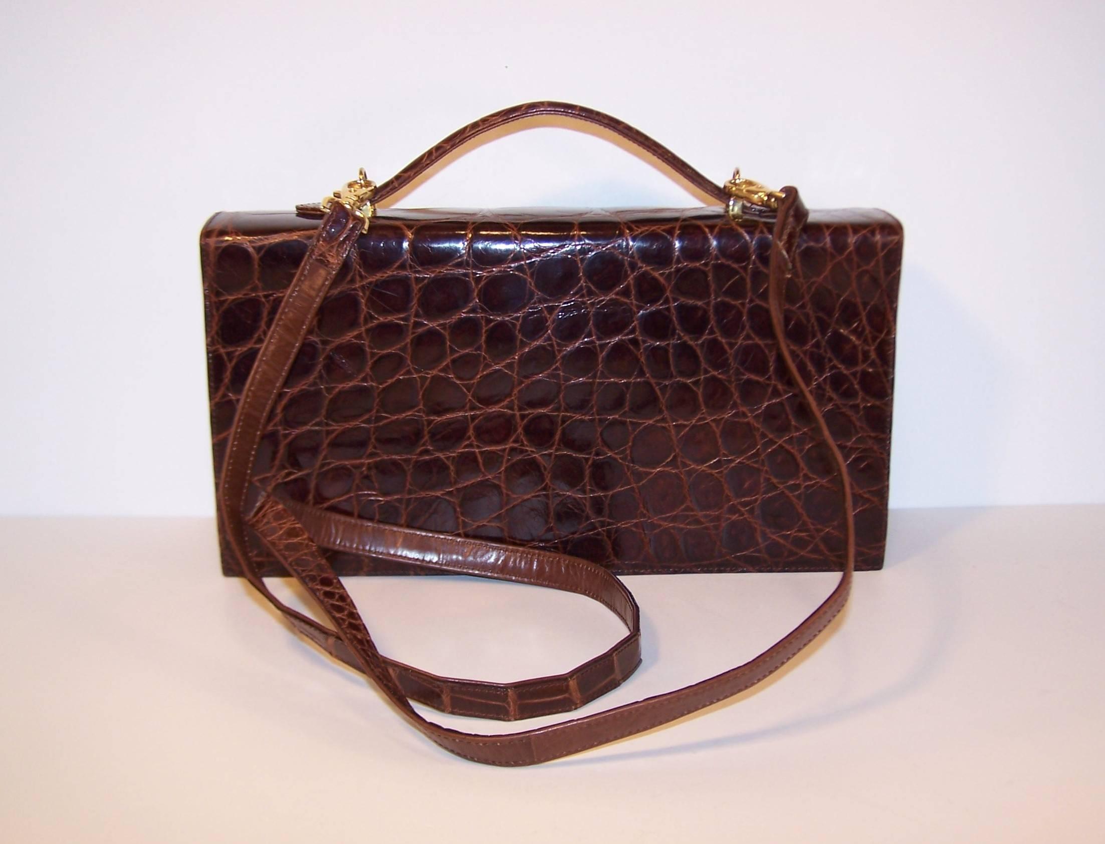 This is a handsome 1970's brown alligator handbag produced in Italy for Saks Fifth Avenue with a classic design and versatile features that make it a perfect pairing for a modern wardrobe.  The rectangular accordion shape is equipped with a snap