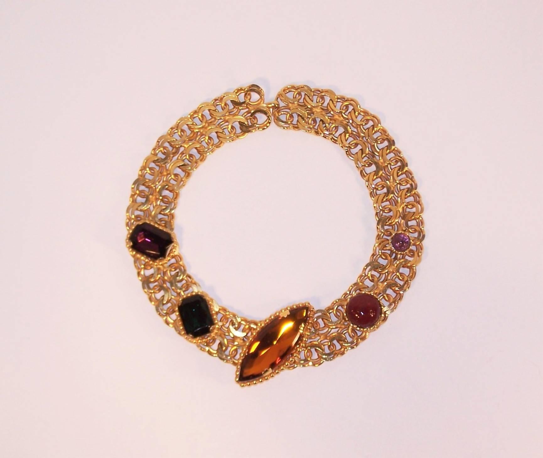 This Dominique Aurientis collar necklace is a stunning statement maker.  Heavy gold tone linked chain serves as a support to giant faceted rhinestones and Gripoix glass framed in both gold beading and twisted casings.  The rich colors of amethyst