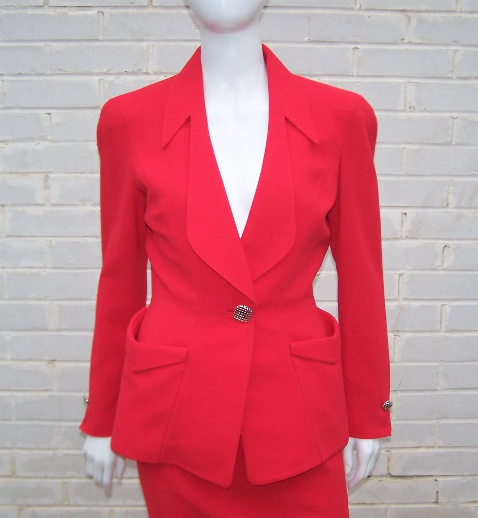 Thierry Mugler's signature futuristic style is evident is this vibrant red skirt suit.  The nipped waist jacket has stylized v-shaped pockets with an open sculptural collar typical of Mr. Mugler's designs and jewelry style silver metal buttons.  The