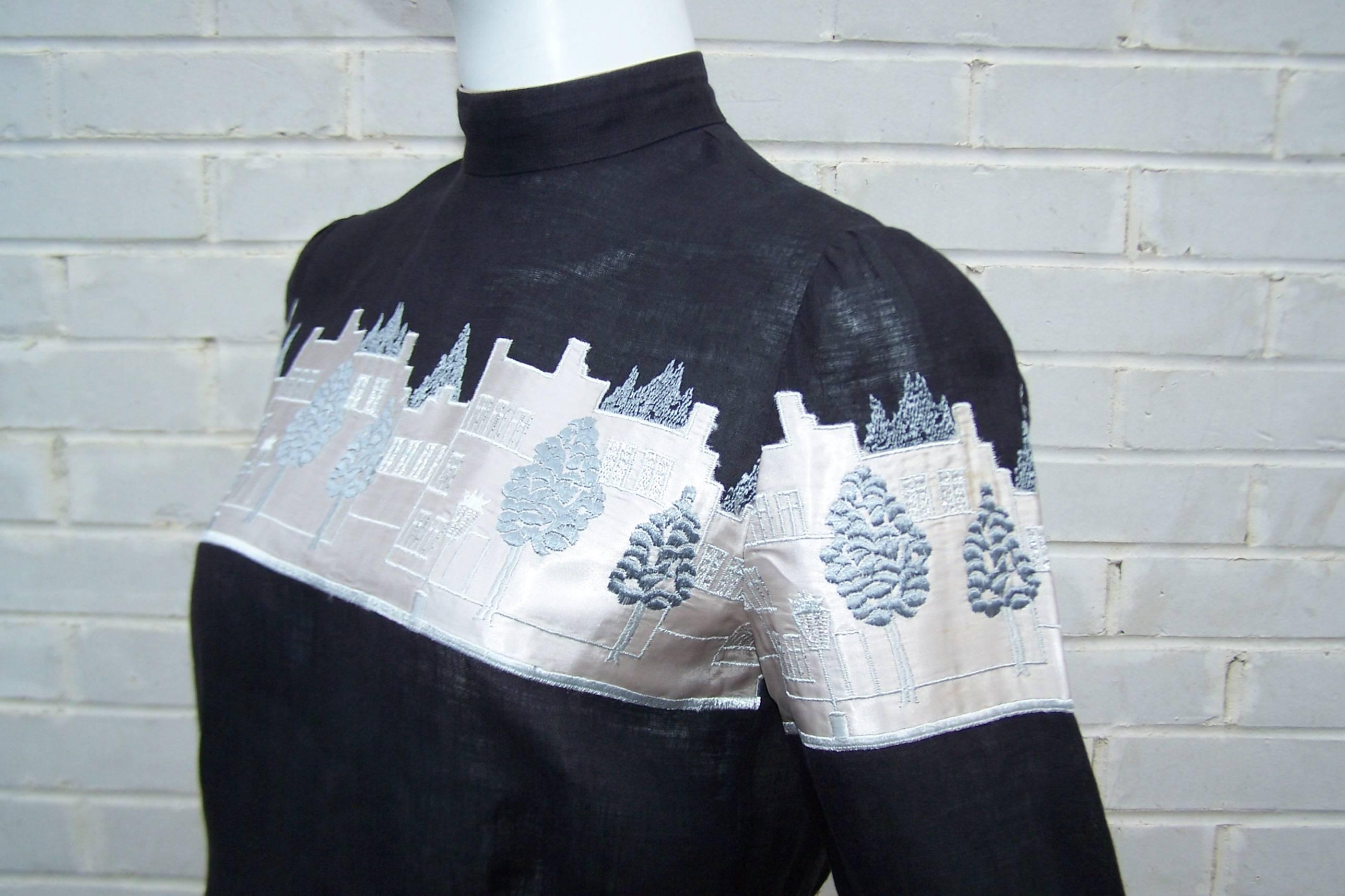 This novelty black linen blouse features a city skyline stretching across the bust and sleeves with a silvery gray satin background and blue-gray embroidery cleverly highlighted with silver threading to resemble lights.  The blouse is a Victorian