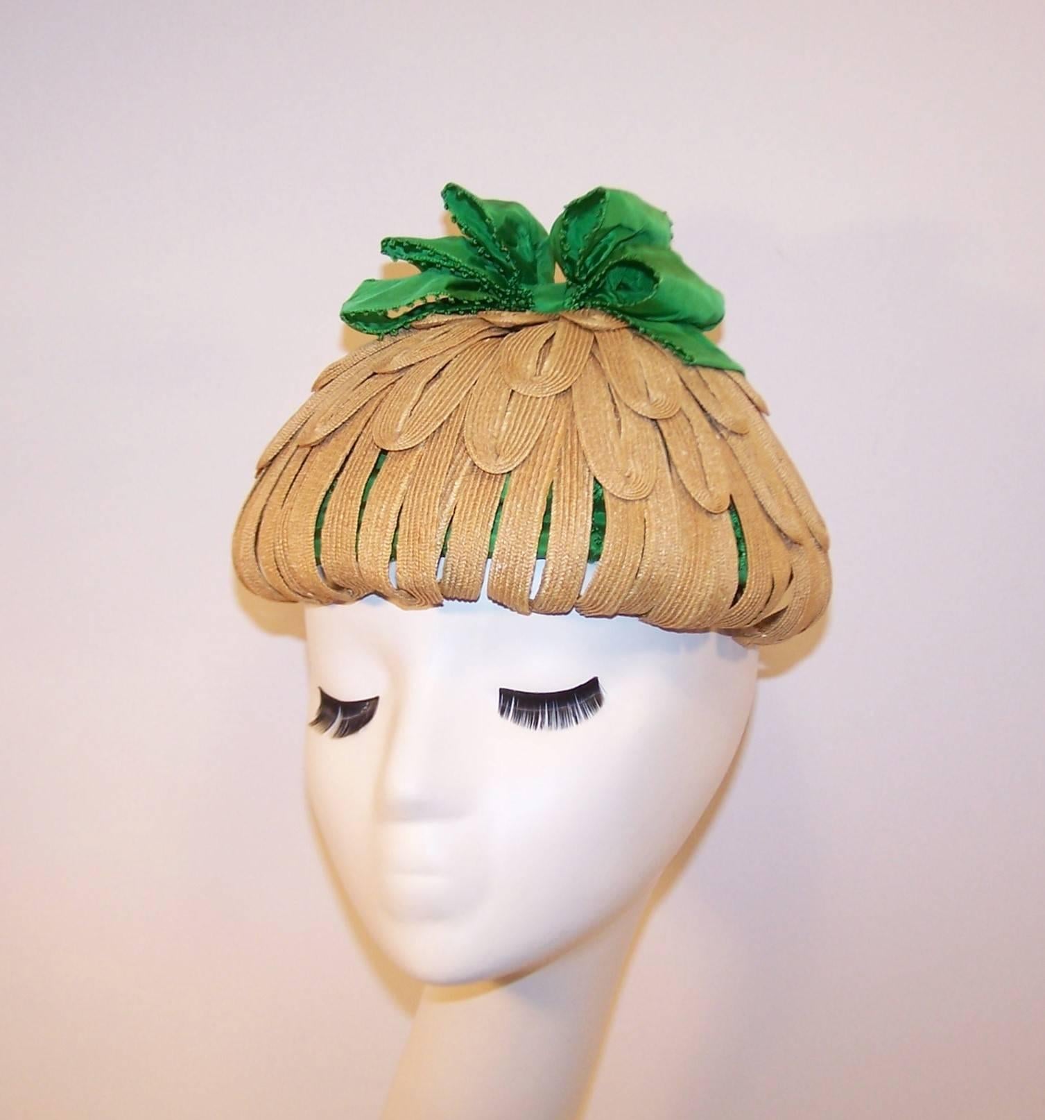 A flower basket of fun!  This whimsical 1950's topper by Bonta Creatrice combines natural straw looped petals with kelly green taffeta ribbon for a playful creation sure to be a conversation piece.  Pair it with a period perfect sundress or a crisp