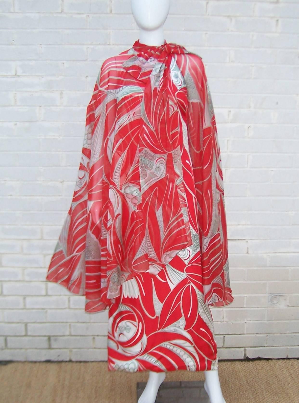 This 1970's dress by Natalie Collett is a fun and fabulous combination of a vibrant tropical print and a dramatic asymmetrical chiffon cape.  The simple columnar halter dress is designed with a not-so-simple graphic fabric in red, white, gray and