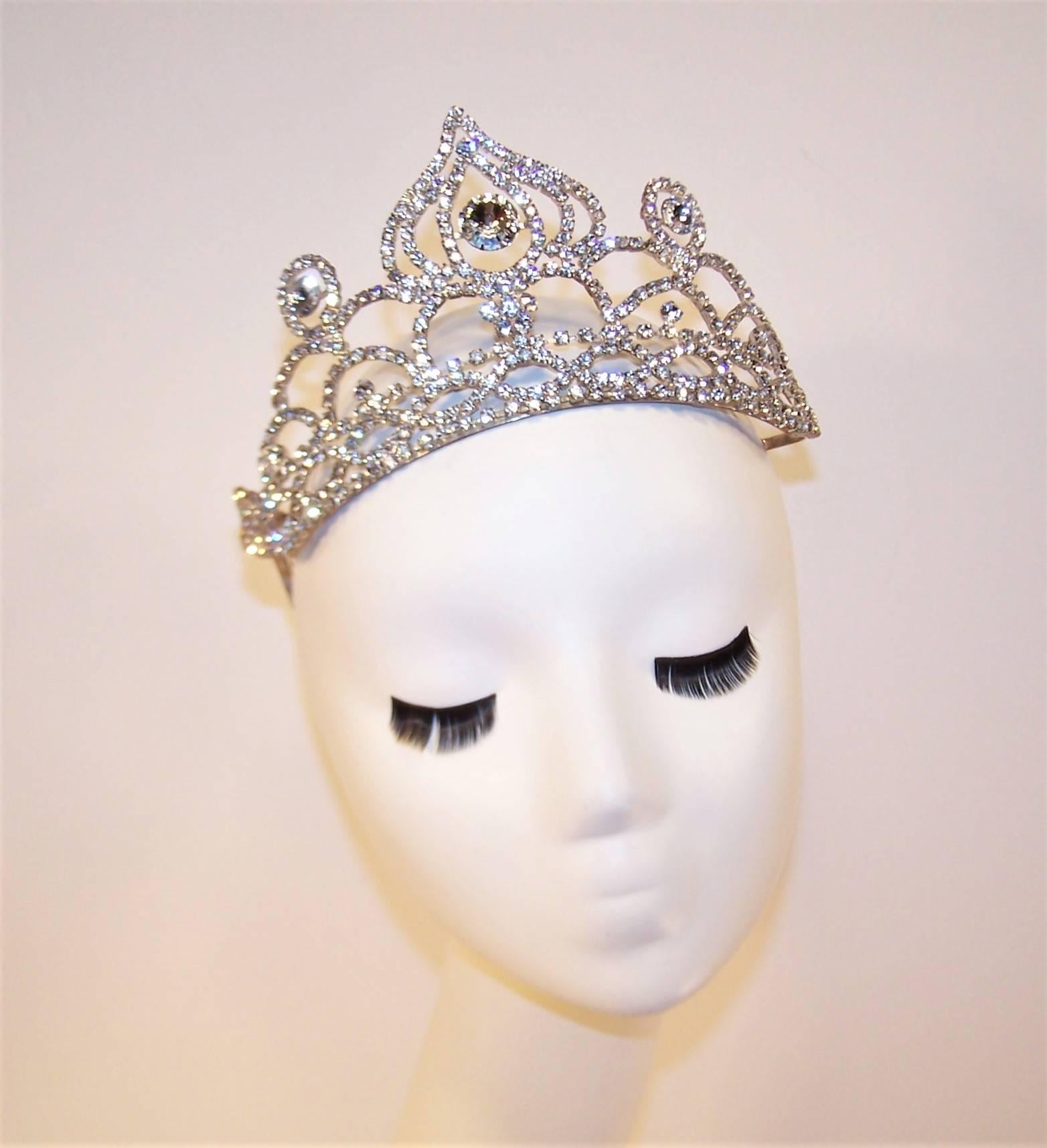 Everything seems more glamorous when wearing a tiara!  Why leave it for a formal occasion?  Don this 1950's crystal rhinestone tiara anytime you need a little royal attention.  Beautifully made with silver tone metal and built-in hair combs to keep
