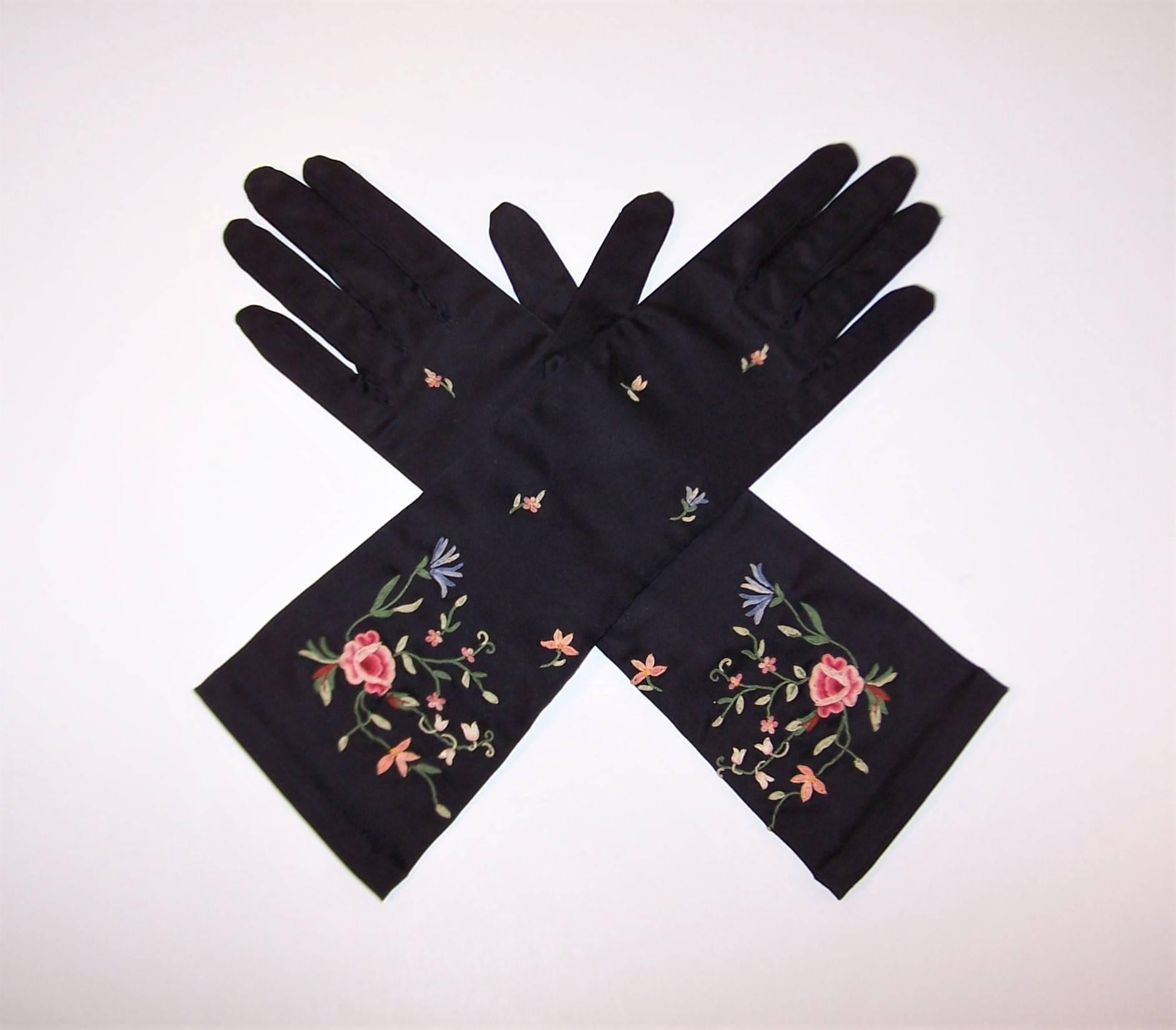 A beautiful pair of gloves is the ultimate in glamour, elegance and style.  These 1950's black stretch satin gloves are 3/4 length with chain stitch floral embroidery in shades of pink, green and blue.  They appear rarely worn though there are some