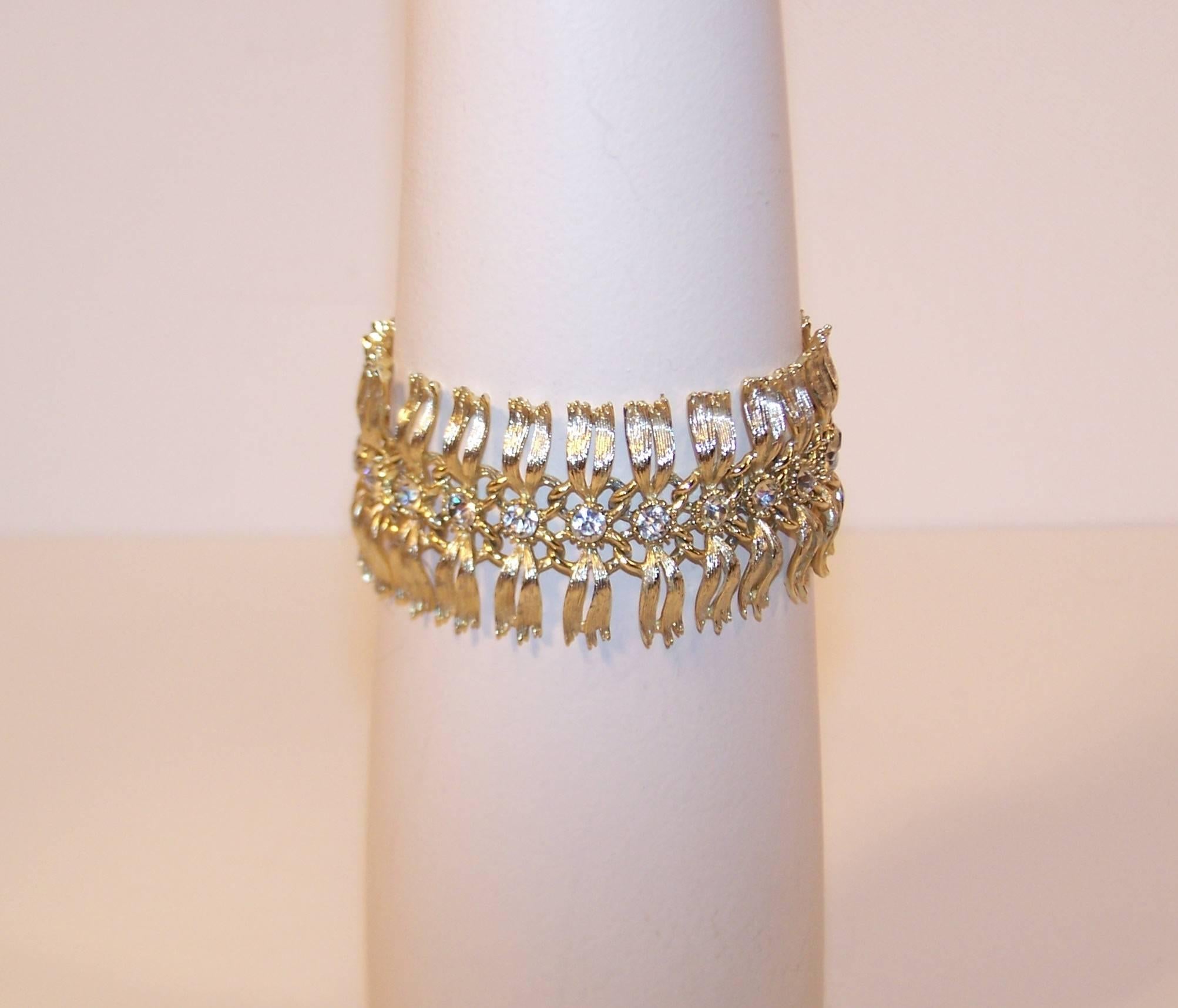 This lovely Lisner bracelet has a serpentine quality to the gold tone articulated links that gives it the ultra glamorous feel of 'dripping with diamonds'.  Each link is a detailed palm frond style leaf accented with a crystal rhinestone which