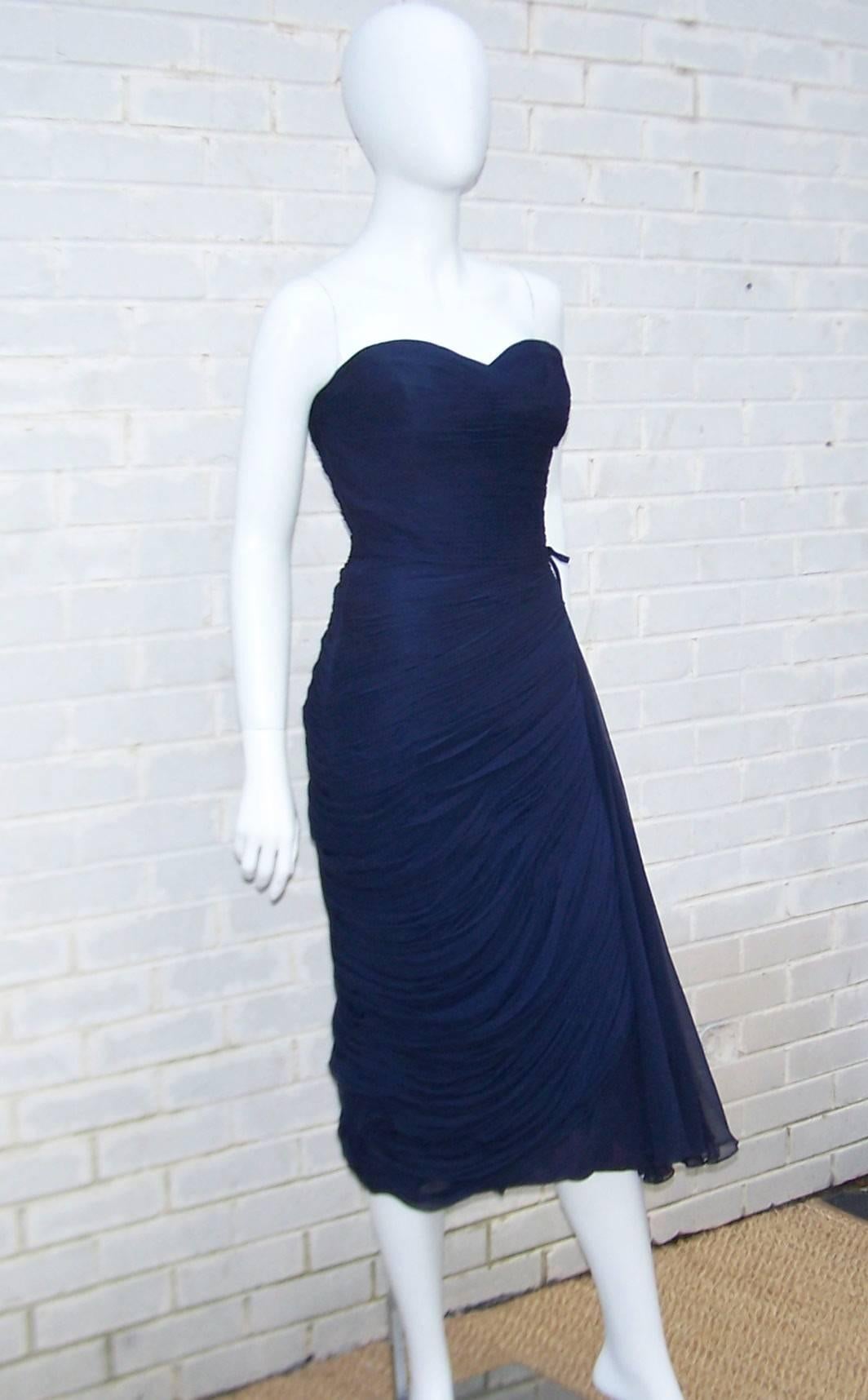 Don this 1950's strapless dress and bring out your inner goddess for an evening under the stars.  Everything about this heavenly silhouette is designed to emphasize the feminine form with dark blue silk chiffon draping and a flowing side panel which