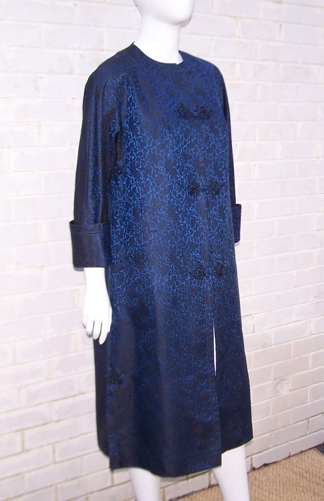 Pair this C.1950 evening coat with a little black dress or a cigarette pant for a touch of Asian exoticism.  The classic mandarin silhouette is enhanced by the black and blue jacquard fabric as well as the detailed stitching at the collar, cuffed