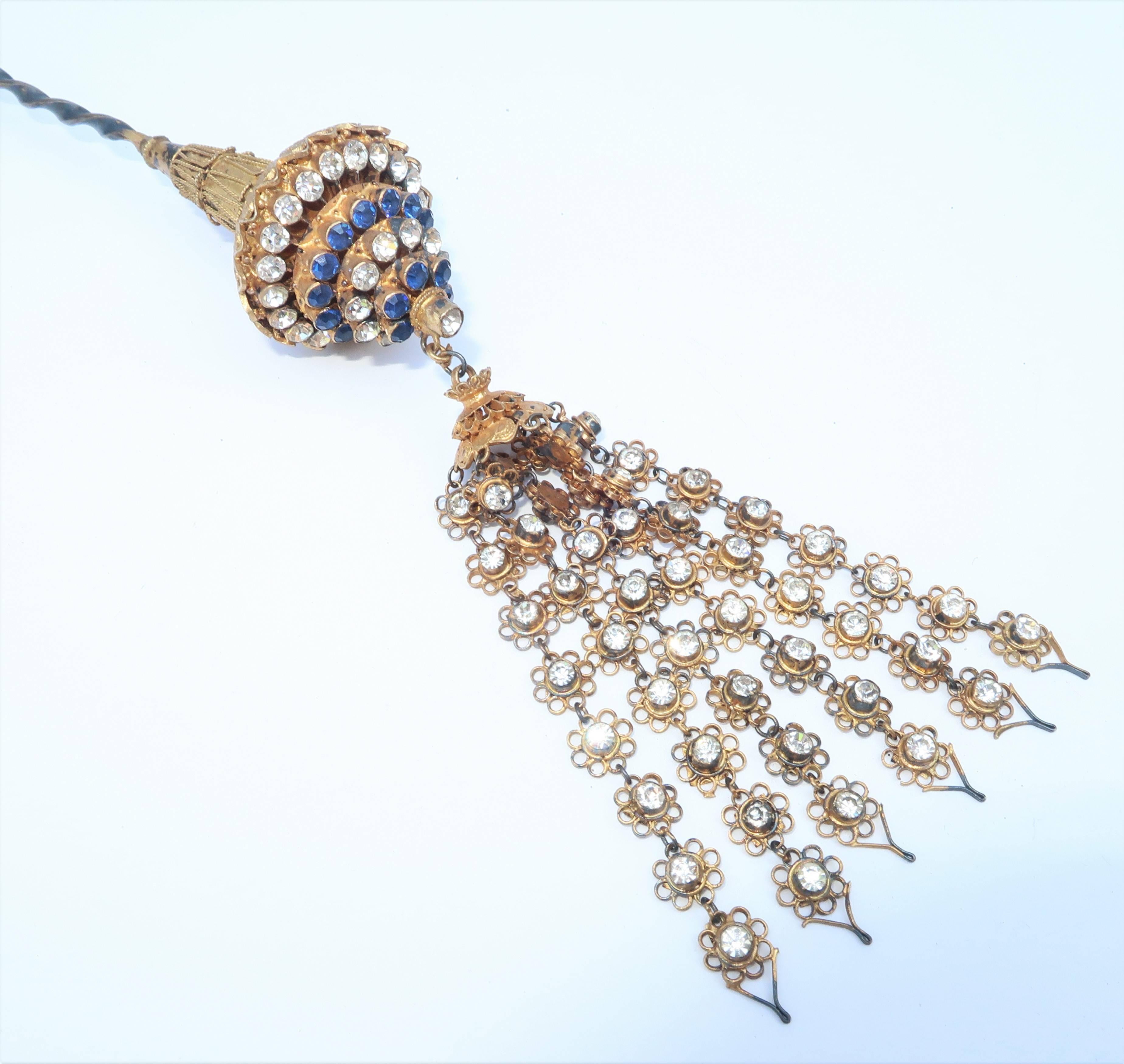 'Hair ornament' aptly describes this beautifully detailed accessory that serves to enhance an updo with an exotic vintage quality.  The twisted stick pin operates well to anchor the sapphire blue and crystal rhinestone embellished filigree finial