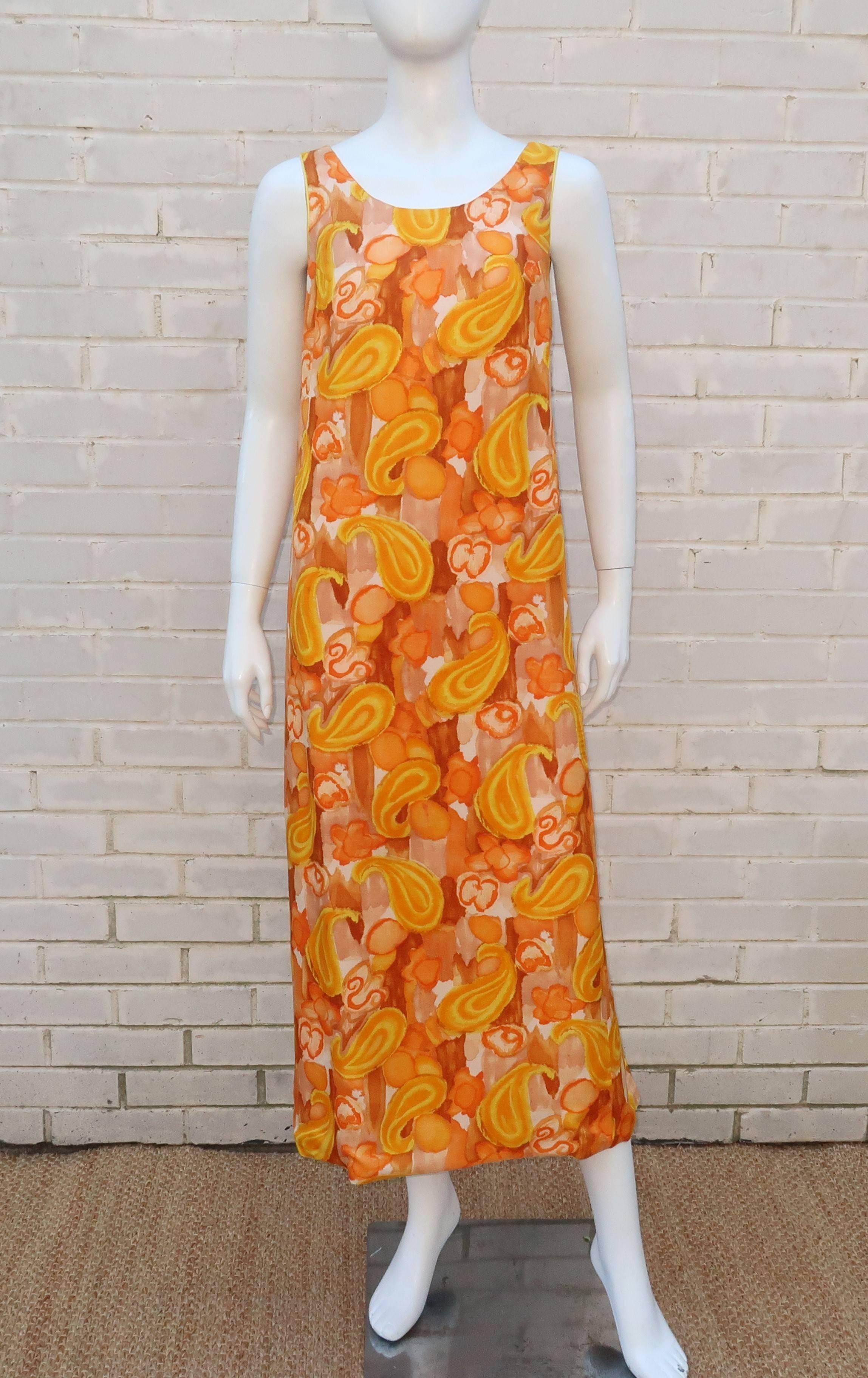 This 1960's apron style caftan is like a sunny day.  The mod floral and paisley print is infused with bright yellow and orange accented by light brown.  The synthetic fabric has the look and feel of dupioni silk and is fully lined in orange.  The