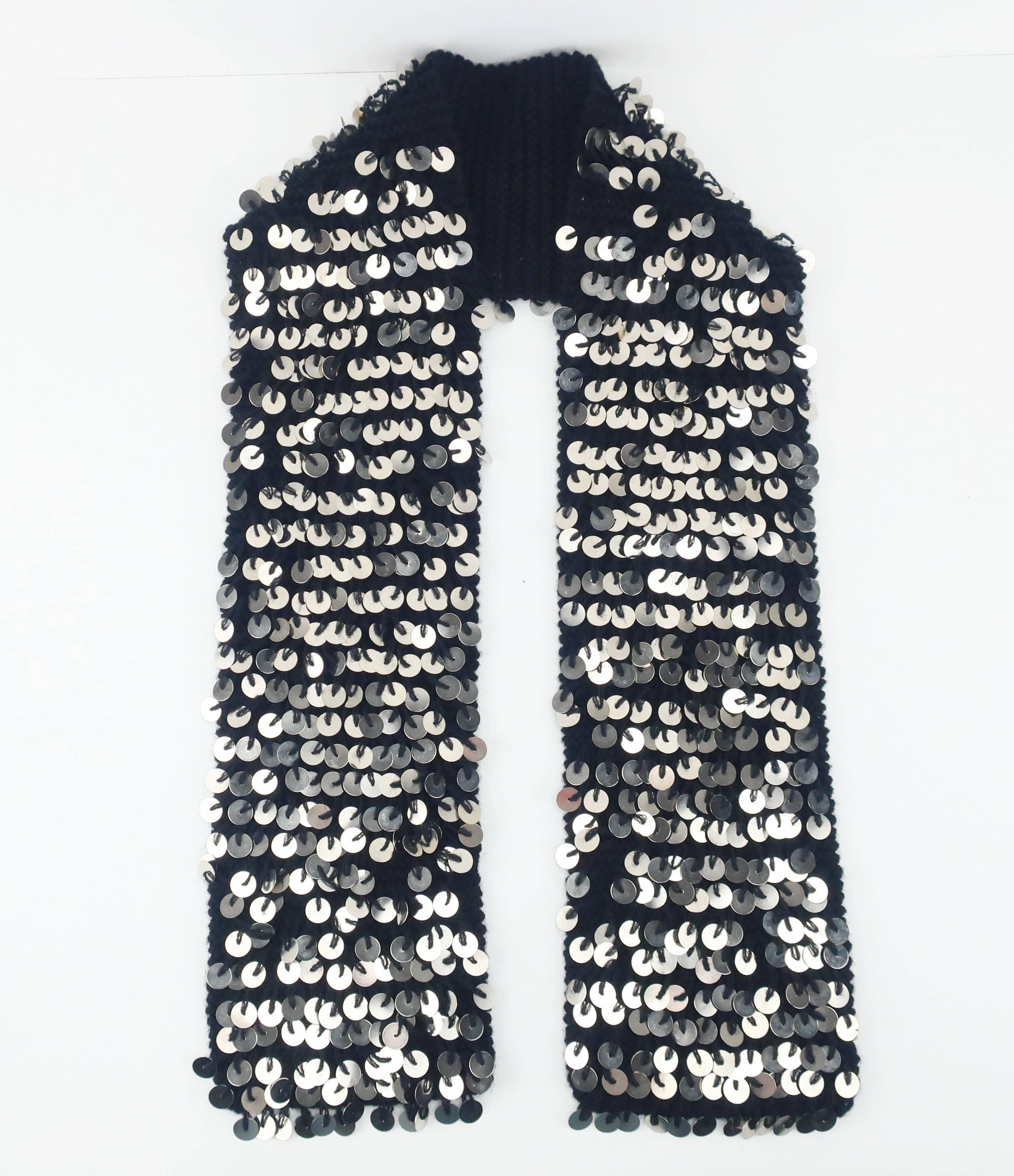 Sensory overload with this C.2000 black wool neck scarf in the form of look, feel and sound!  The silver medal medallions sewn onto the hand knitted scarf provide sweet sound effects akin to a charm bracelet.  They also catch the light and shimmer