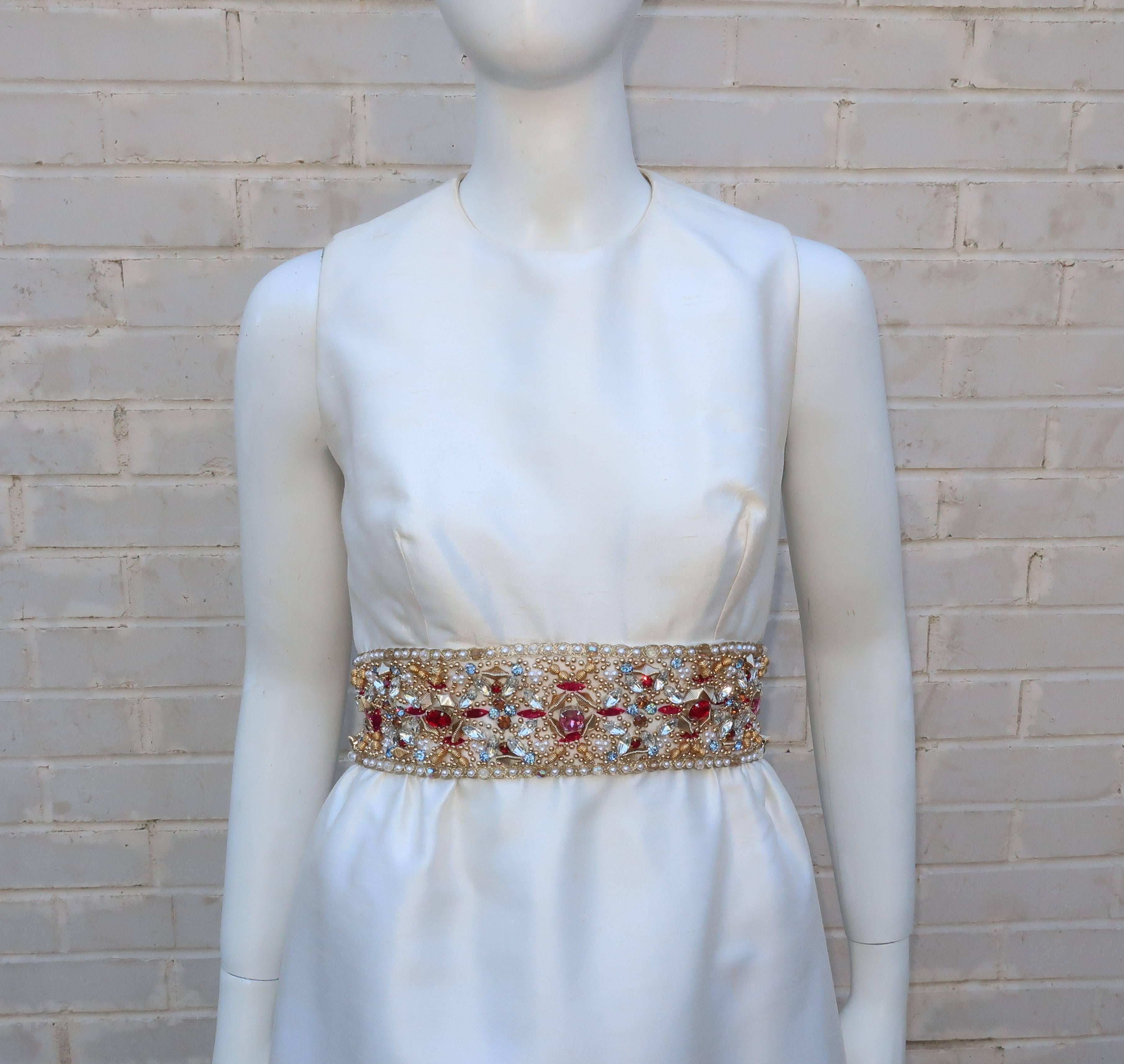 Prepare to be bedazzled!  This 1960's Kent Originals evening dress in a crisp white dupioni fabric is a classic 1960's empire waist silhouette with a couple of eye catching features.  First and foremost is the dazzling embellished empire waist with