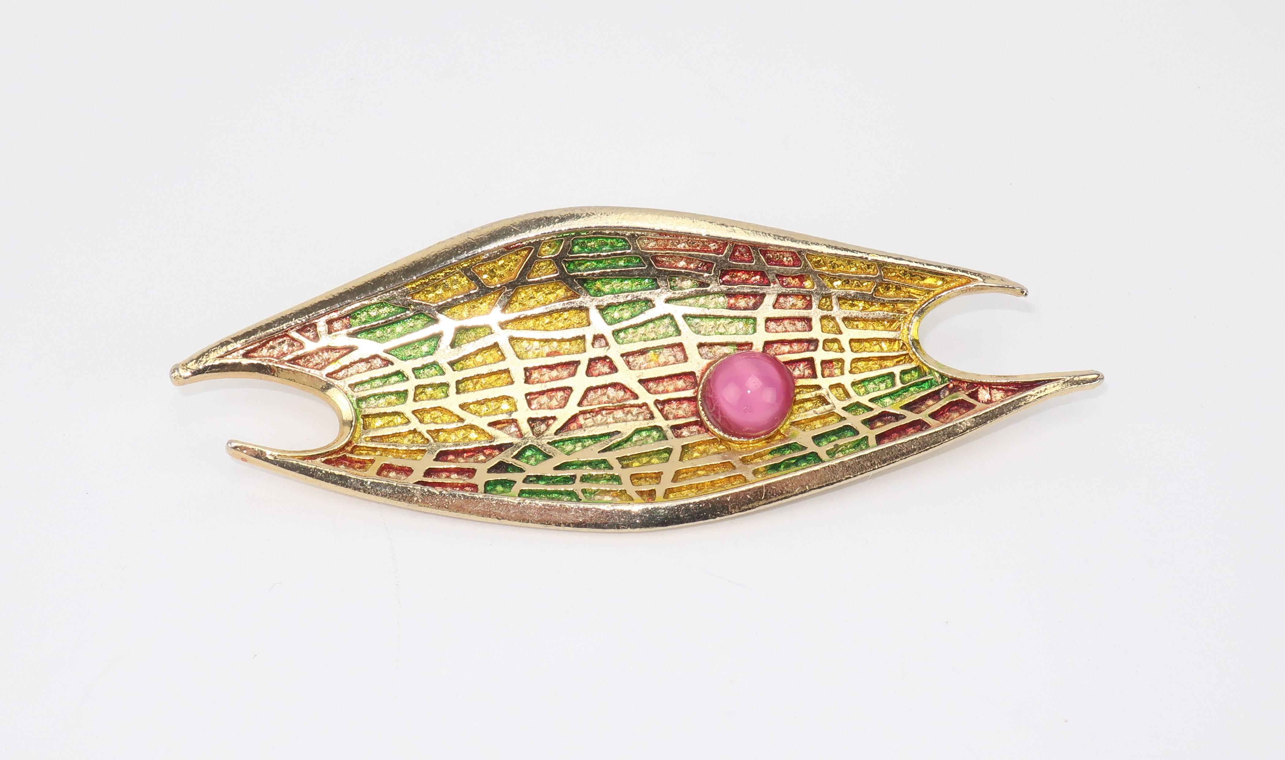 Turn heads with this abstract modernist gold tone brooch.  The unusual shape of the brooch is enhanced by the texture of the design with a colorful surface resembling an acid etch effect layered with a spider web style grid.  The concave surface is