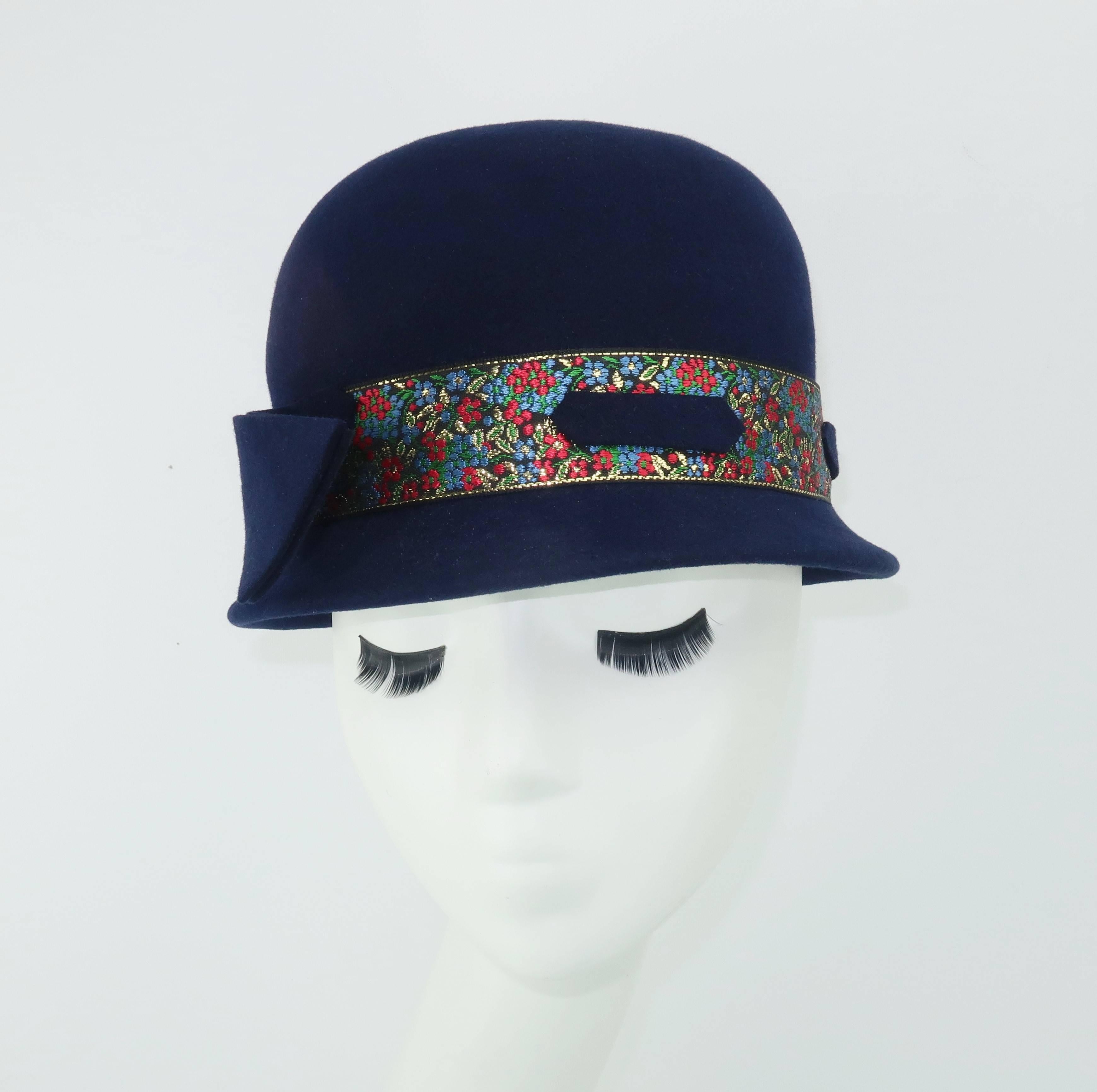 Give the classic bowler hat a ladylike twist and voila!  This adorable navy blue wool felt hat appears and provides a stylish topper that provides warmth and charm to a wintry ensemble.  The shallow brim is charmingly decorated with a floral brocade