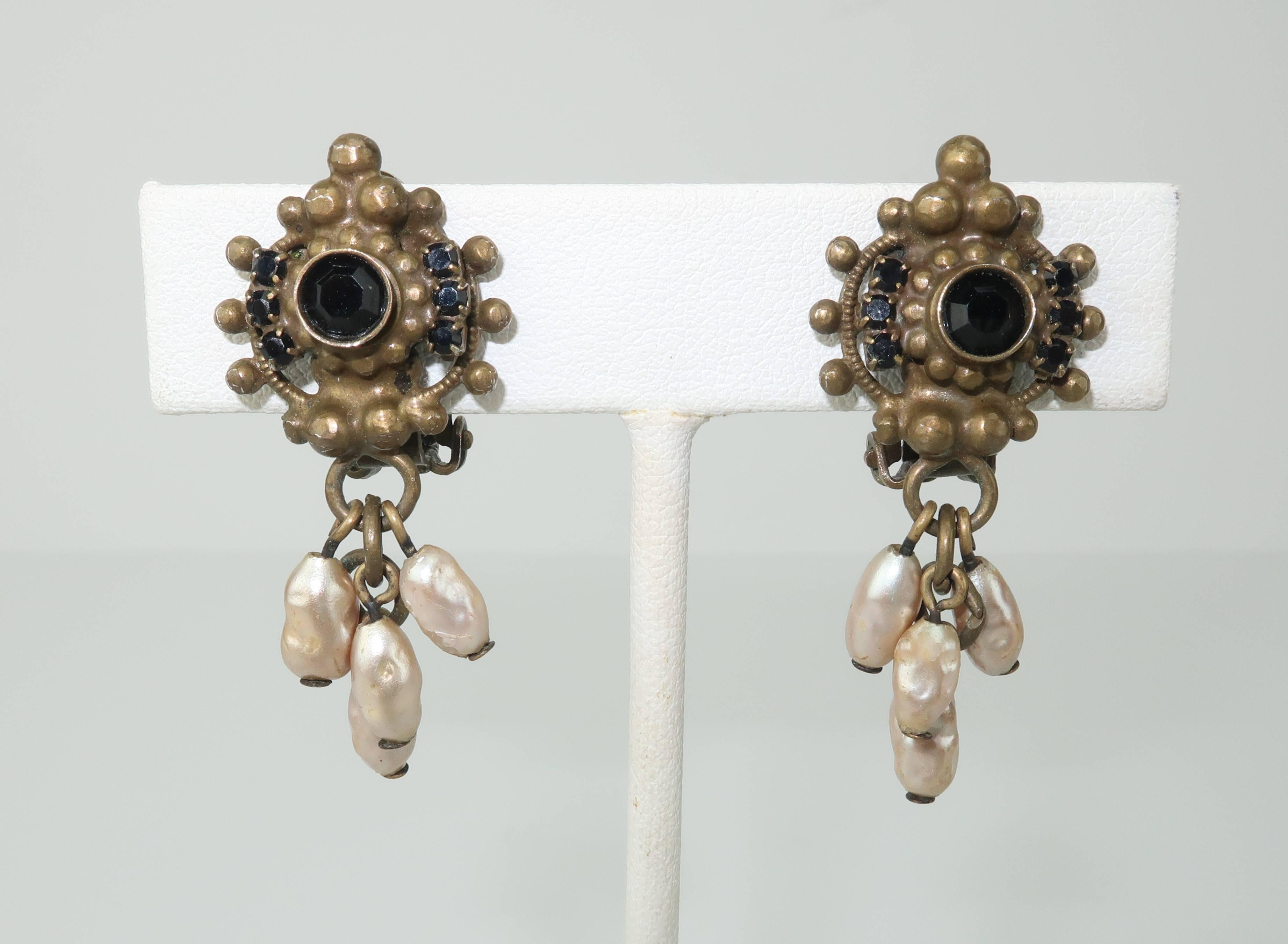 These 1980’s earrings by Sorrelli deserve a closer look.  The beautiful detail of the handcrafted antique brass setting is accented with garnet colored crystals and faux freshwater pearl dangles.  You will swear they are Victorian era though there