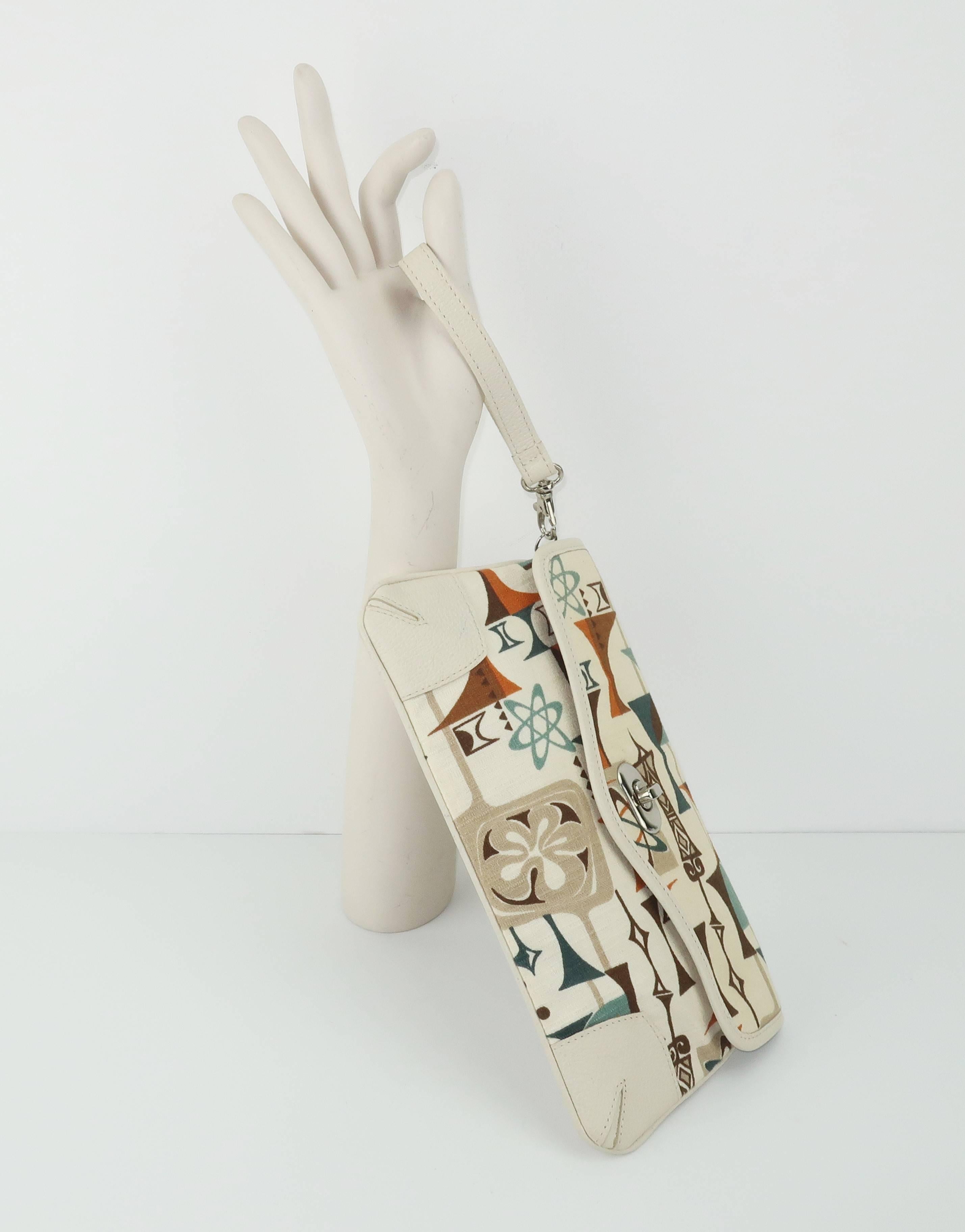 This contemporary handbag by American designer, Dorothy Barrick, is a fun combination of an atomic age bark cloth textile and bone leather.  The 1950’s inspired print graphically mixes browns, taupe, green and teal on a creme background.  The turn