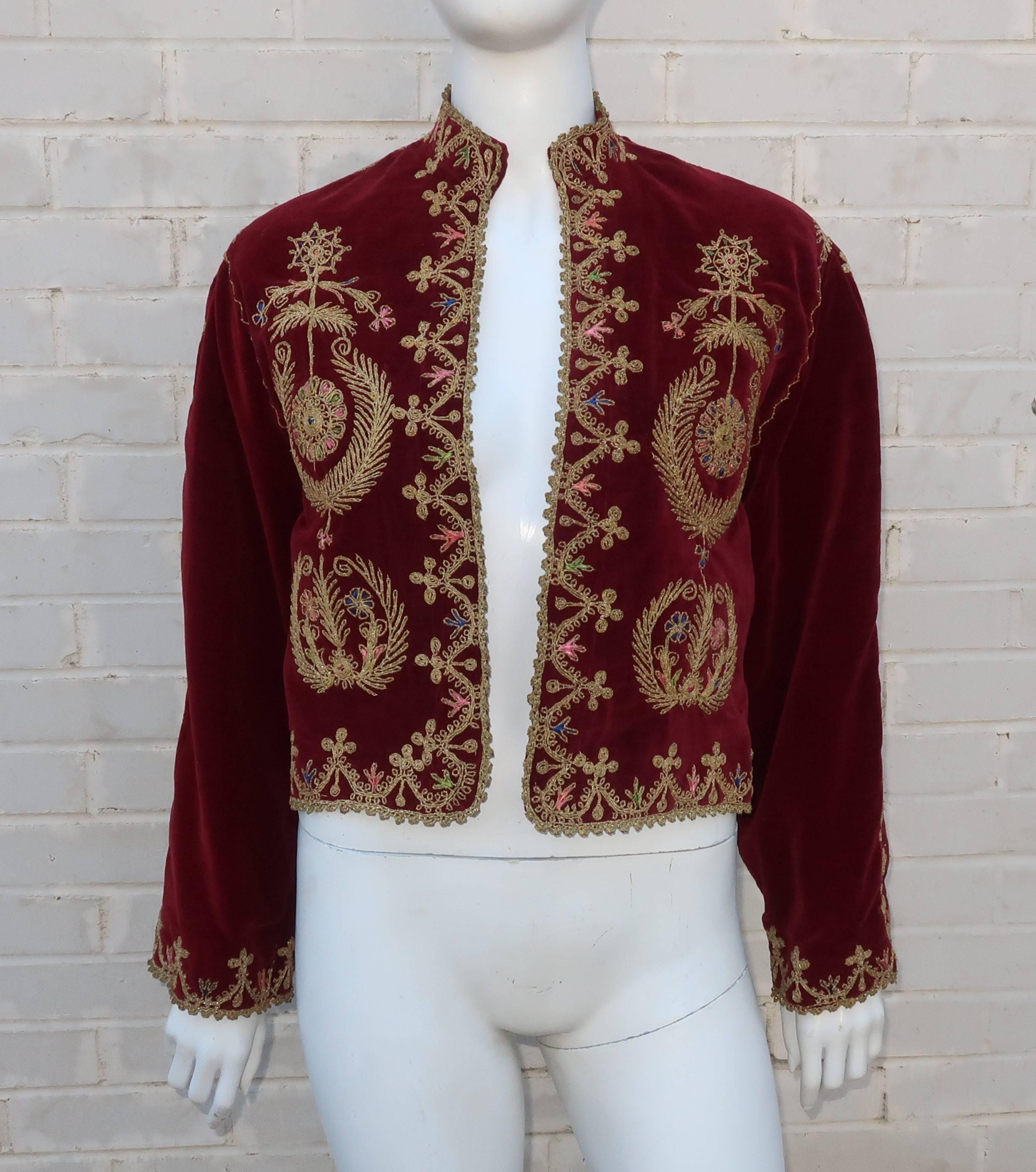 Add a dash of the exotic to your wardrobe with this 1970’s ruby red velveteen Moroccan jacket.  The cropped silhouette is accented with a mandarin style collar, open front and modified bell sleeves.  The abstract floral embroidery incorporates blue,