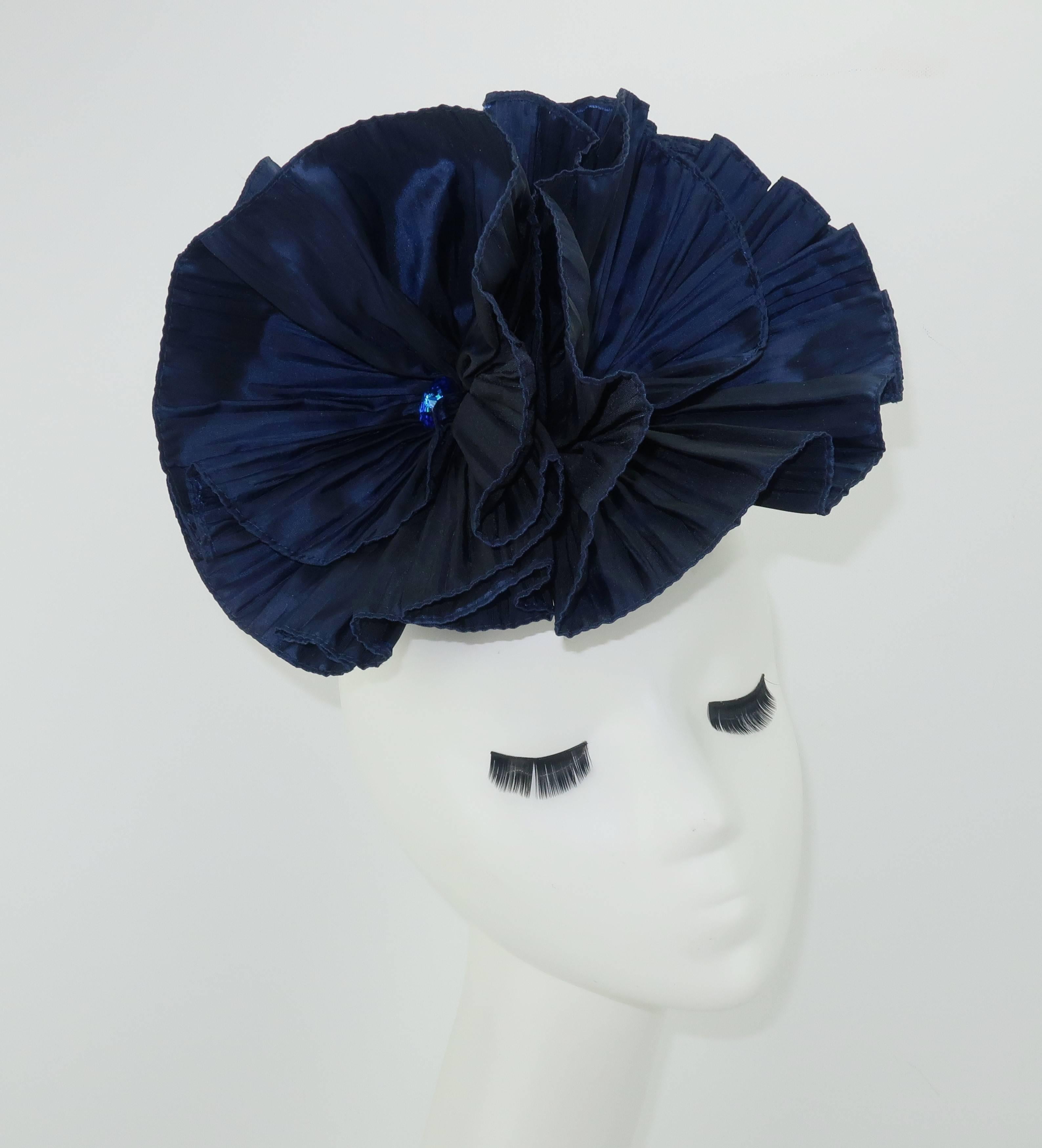 Royal wedding anyone?  Fascinators have a well earned place in the fashion history of millinery design.  The word itself means to bewitch and indeed this 1980’s version does it quite well in blue micro pleated taffeta.  The fabric is shaped into two