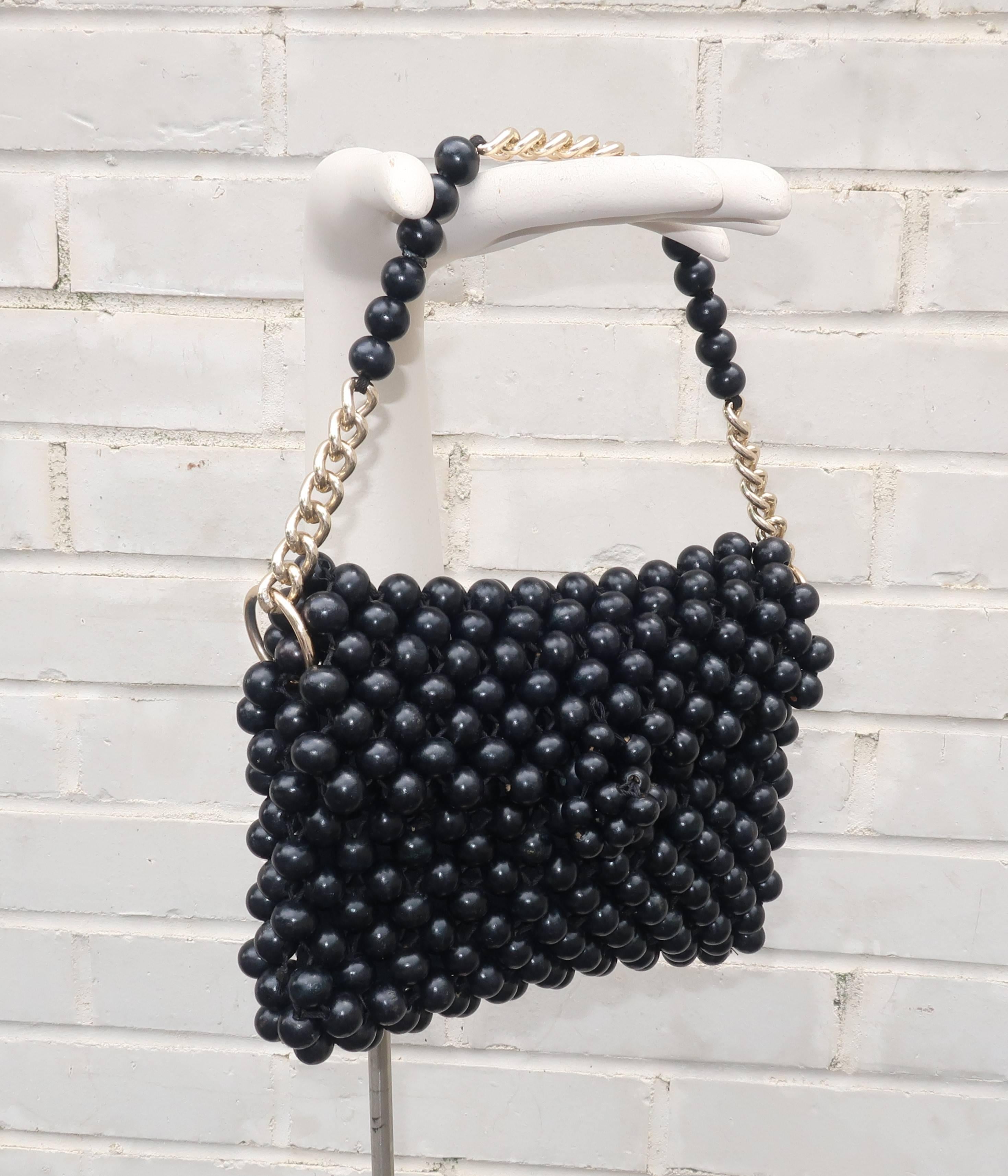 The fun combination of a mod aesthetic and bohemian look gives this Japanese 1960's black wood bead handbag with gold tone chain link handle a period perfect vibe.  The front flap secures with an elasticized closure and the fabric lined interior