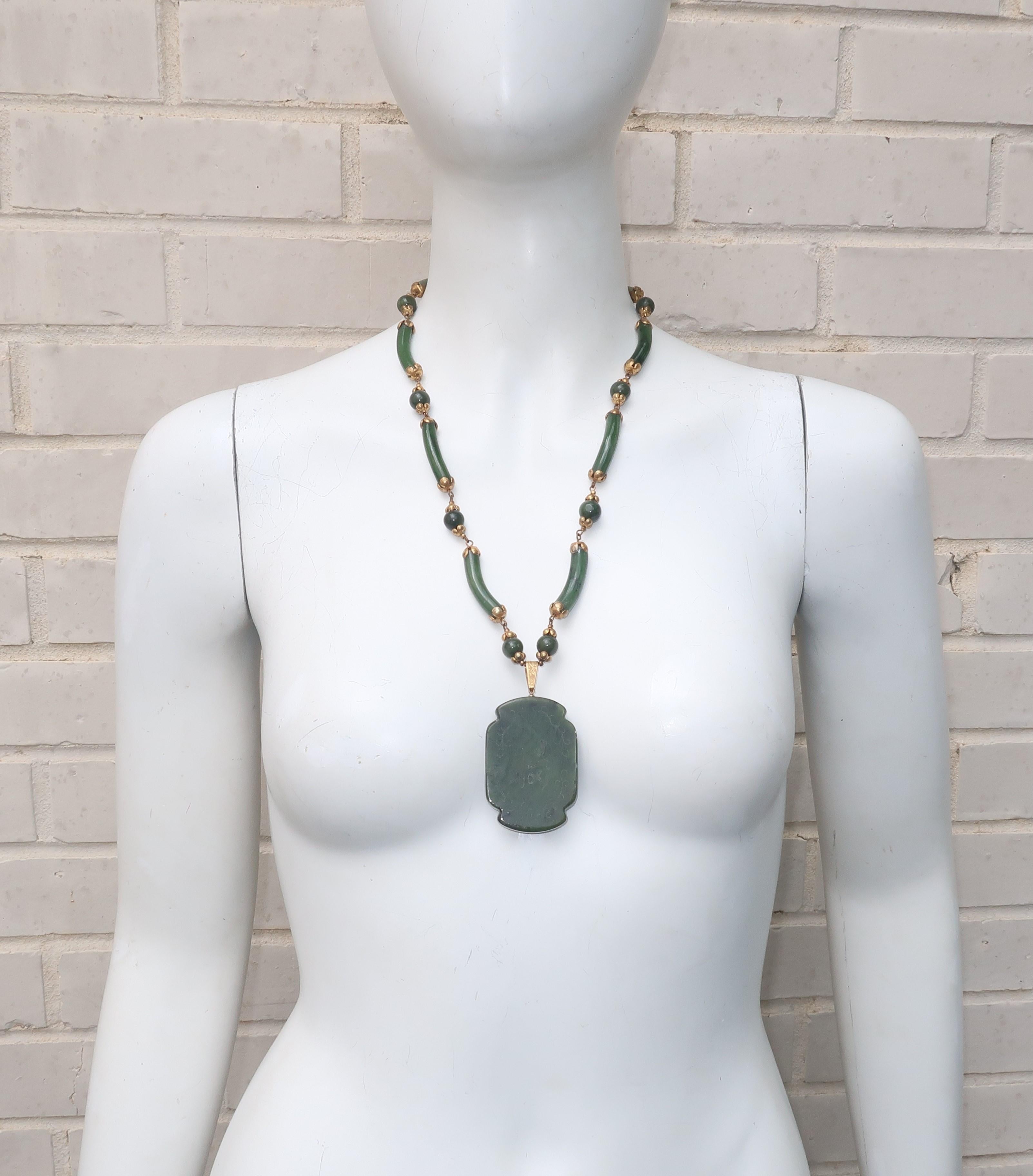 This 1950's Miriam Haskell 'spinach' green jade medallion necklace is reminiscent of 1920's Art Deco jewelry with an exotic aesthetic.  The jade medallion is etched on one side with characters and the other side with a tranquil bucolic scene.  The