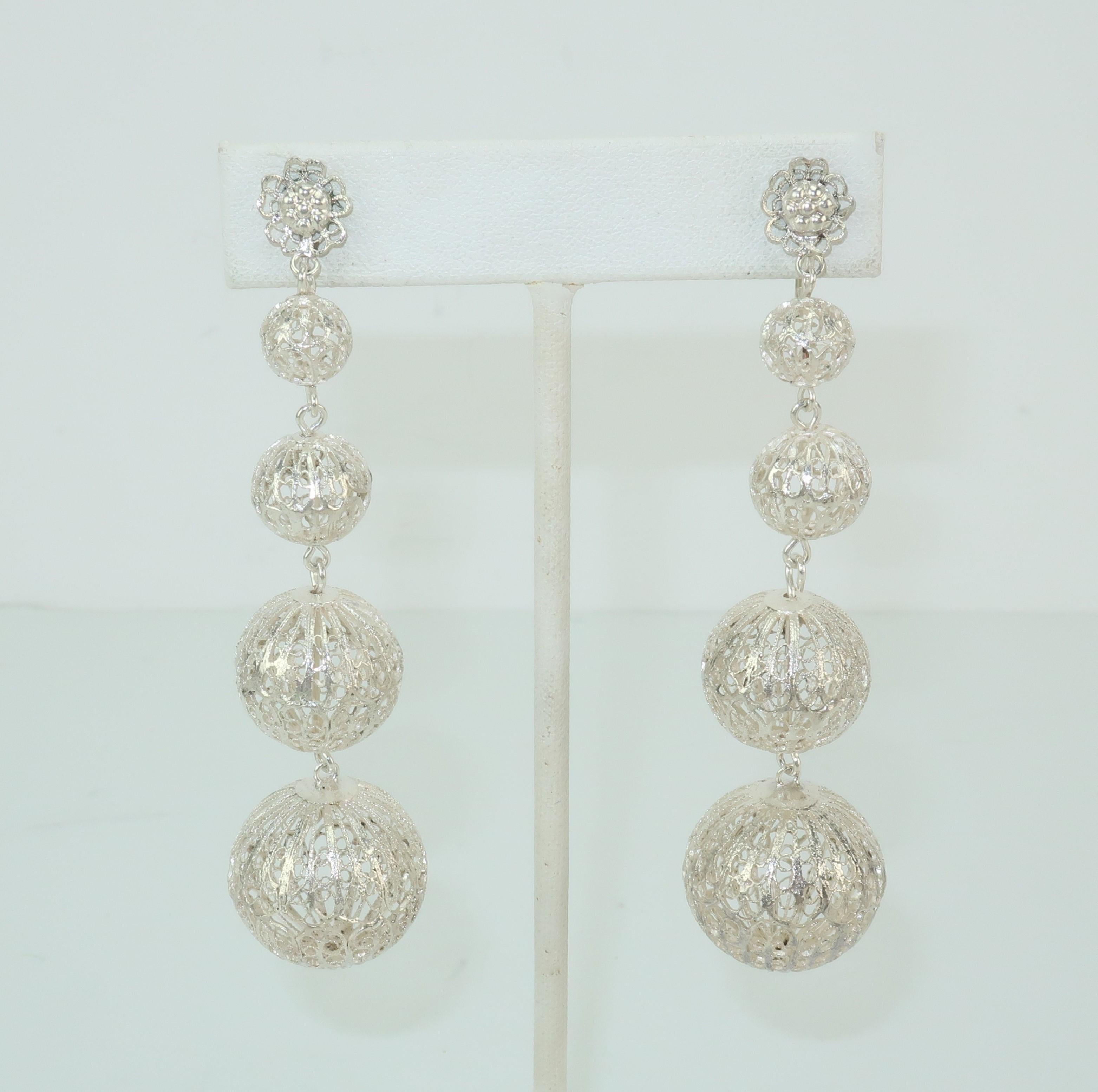 These vintage silver metal earrings are delicate and light as a feather but pack a visual punch.  The four graduated orbs are an intricate filigree design attached to a floral shaped base with screwback closures.  They are not hallmarked though they
