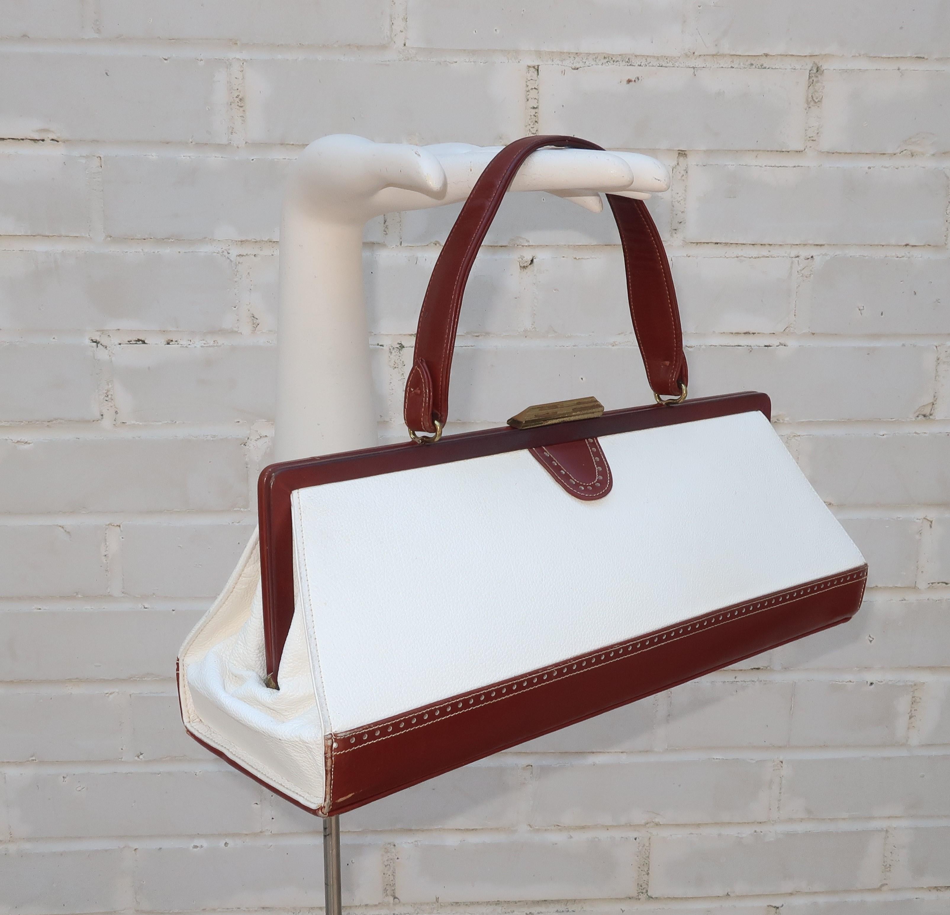 A classic spectator look never goes out of style!  This 1950’s J. Miller handbag features a unique elongated shape fabricated from smooth brown and pebbled white two-tone leathers with a classic spectator perforated design.  The push button gold