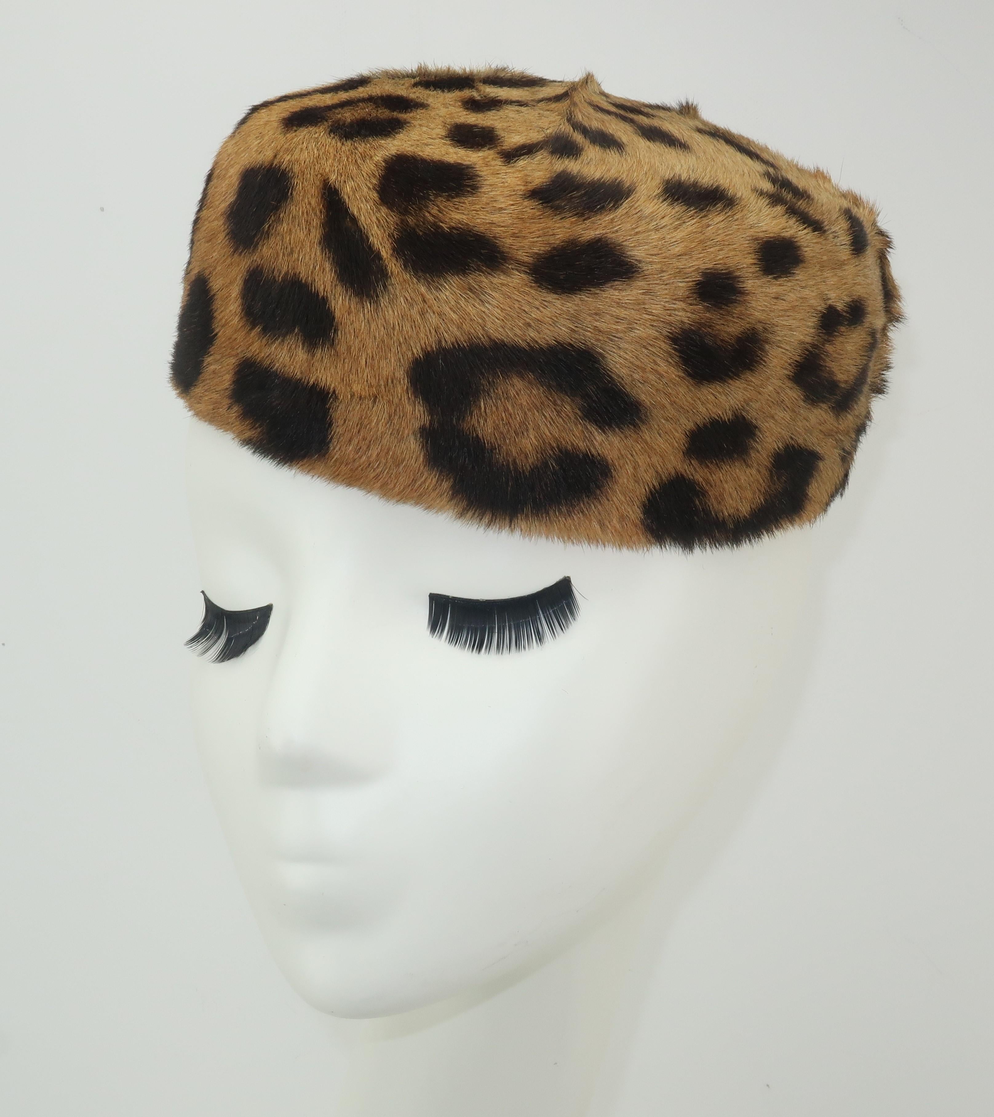 Add an exotic flavor to your wardrobe with this fashionable leopard printed fur pillbox hat.  The minimalist shape can be worn forward, back or cocked to one side.  Lined with grosgrain black fabric and accompanied by a vintage hat box from Muse’s,