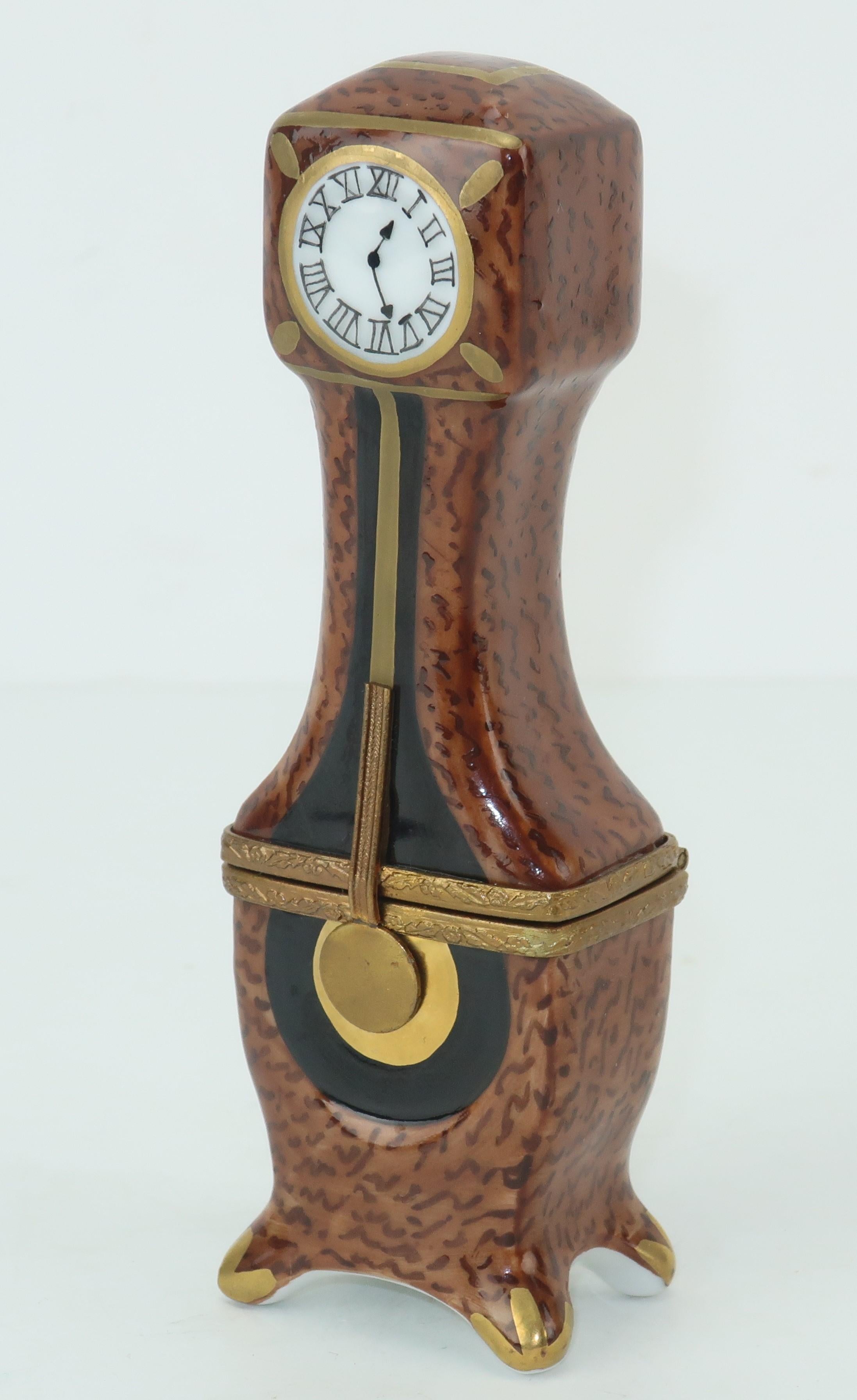 Tick tock!  This French Limoges porcelain trinket box resembles a miniature grandfather clock complete with a pendulum.  It is charmingly hand painted in shades of black, gold and browns with a faux burl wood finish and a Roman numeral face.  The