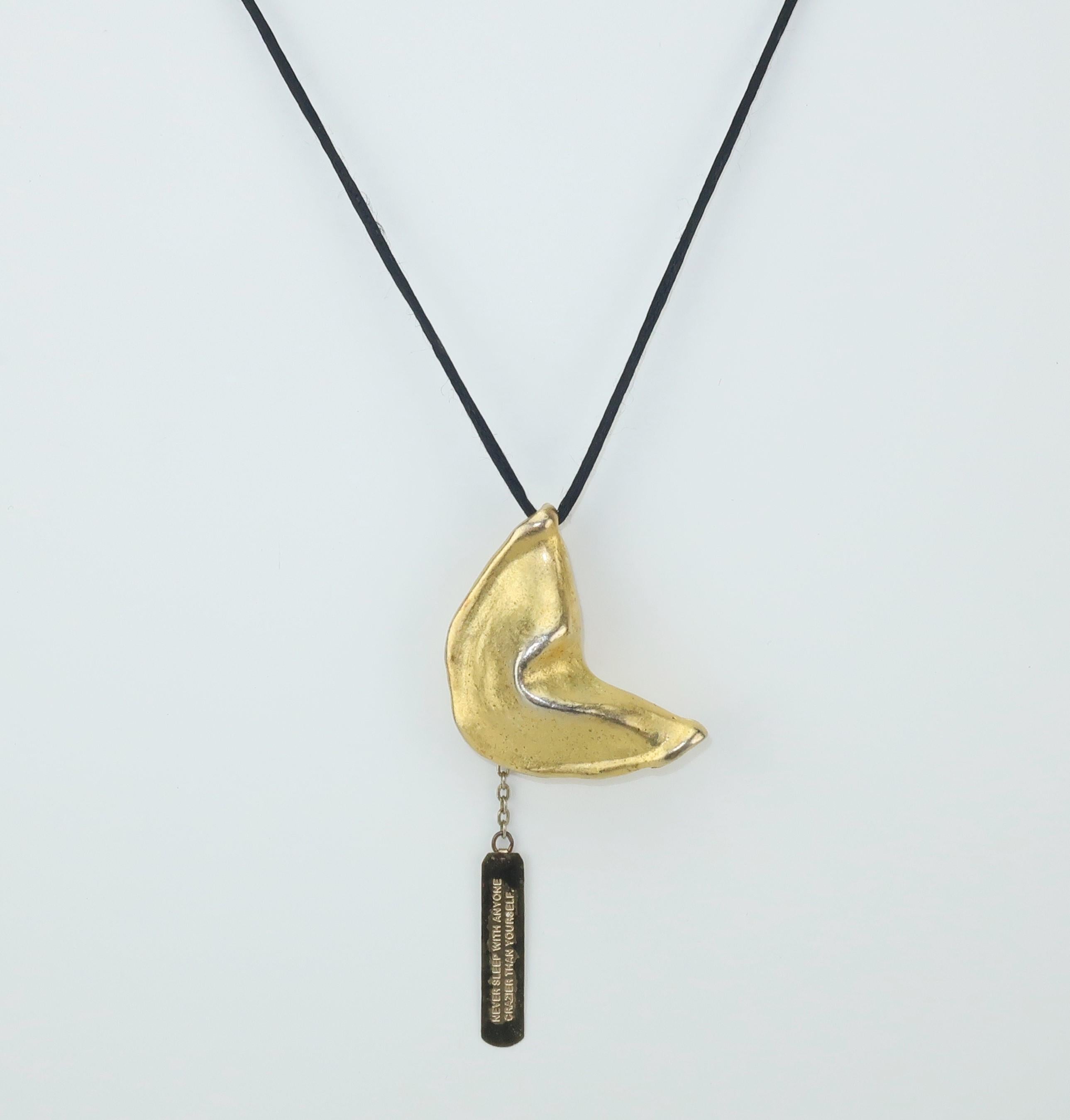 This witty fortune cookie necklace is a more contemporary design by the famous company founded by Miriam Haskell in the early 20th century.  The matte gold tone cookie is suspended by a black silk cord and is accompanied by a fortune which