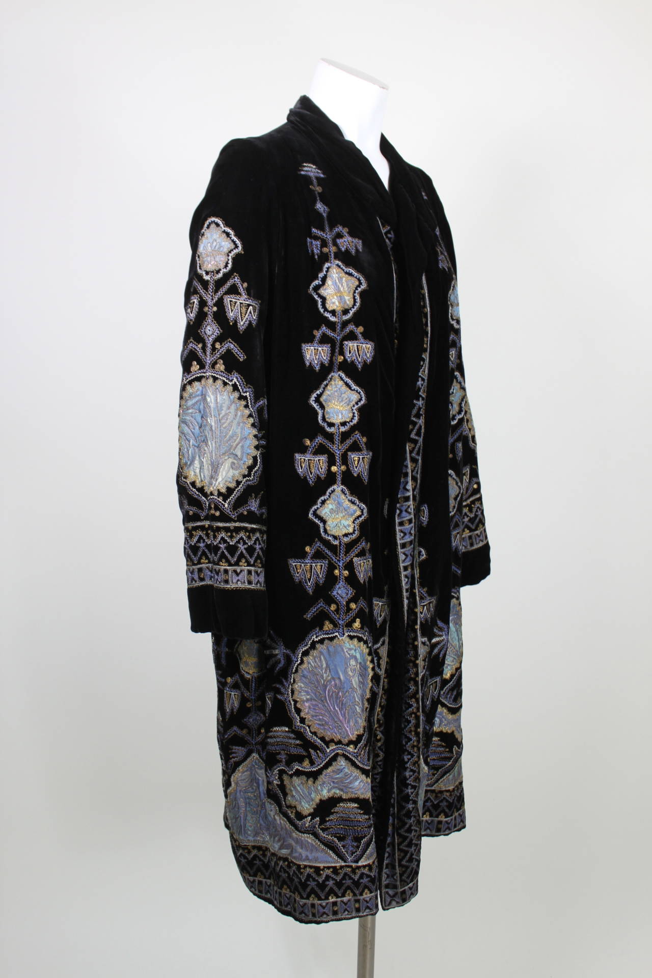 Gorgeous purple, blue, and metallic gold are embroidered throughout the luxe black velvet 1920s evening coat. The lining has been replaced, but the original tag remains intact.