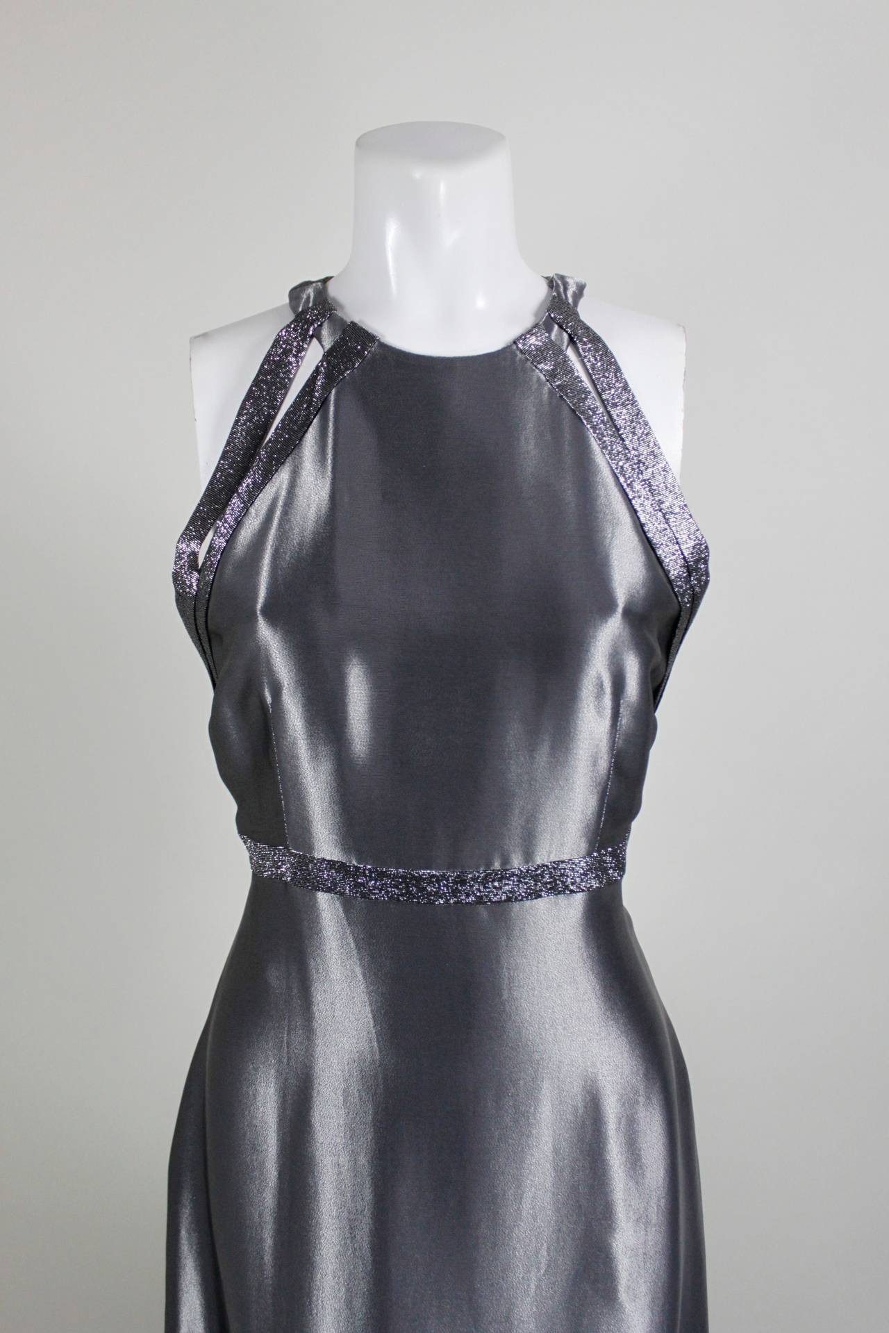 This sporty gown from Genny features gunmetal wet look metallic fabric trimmed with gorgeous iridescent lurex. The racer neckline is modern, chic, and interesting.