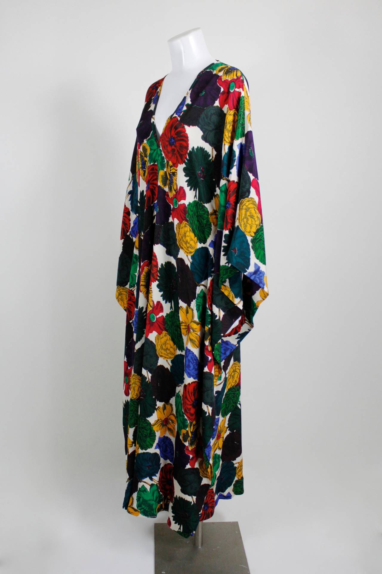 This is a gorgeous 1960s multicolored floral caftan. The print is bold and beautiful from afar, and is even more stunning up close: the flowers have a chalky black graphic outline, and some flowers feature a contrasting color beneath to help the