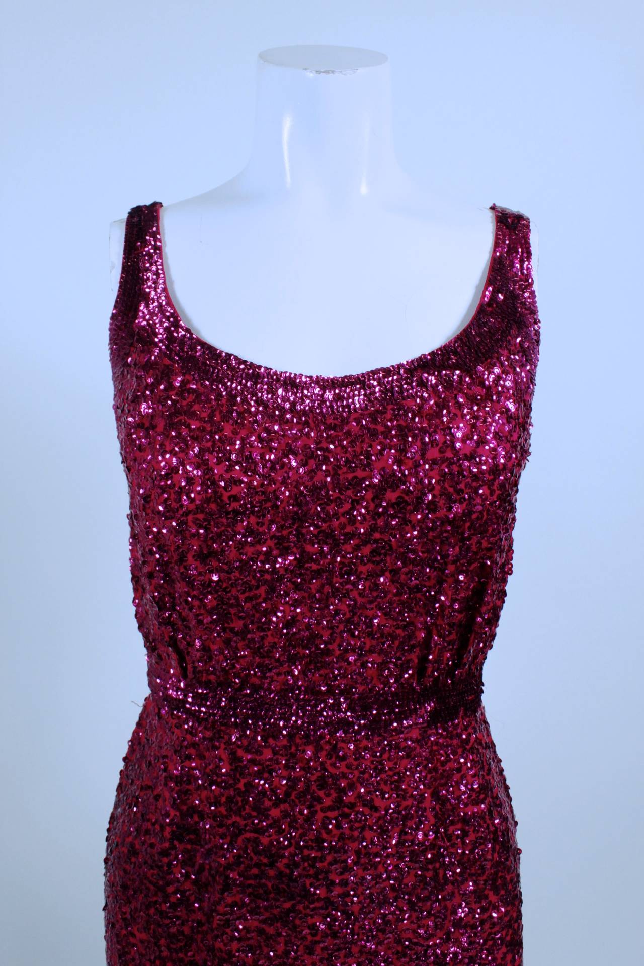 This gorgeous gown is evocative the iconic Norman Norell “mermaid” look. A luxe raspberry silk crepe sheath is covered in hand-sewn sequins, adding glimmer, texture, and glamour. The gown is fully lined, and zips in back. Please note that because