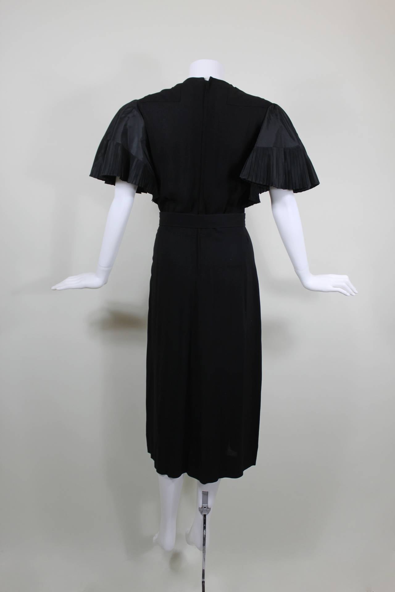 This fabulous cocktail dress from iconic Hollywood designer Adrian is done in black crepe and features gorgeous pleated taffeta statement sleeves.

Measurements--
Bust: 36 inches
Waist: 27 inches
Hip: up to 40 inches
Length, Shoulder to Shoulder: 18