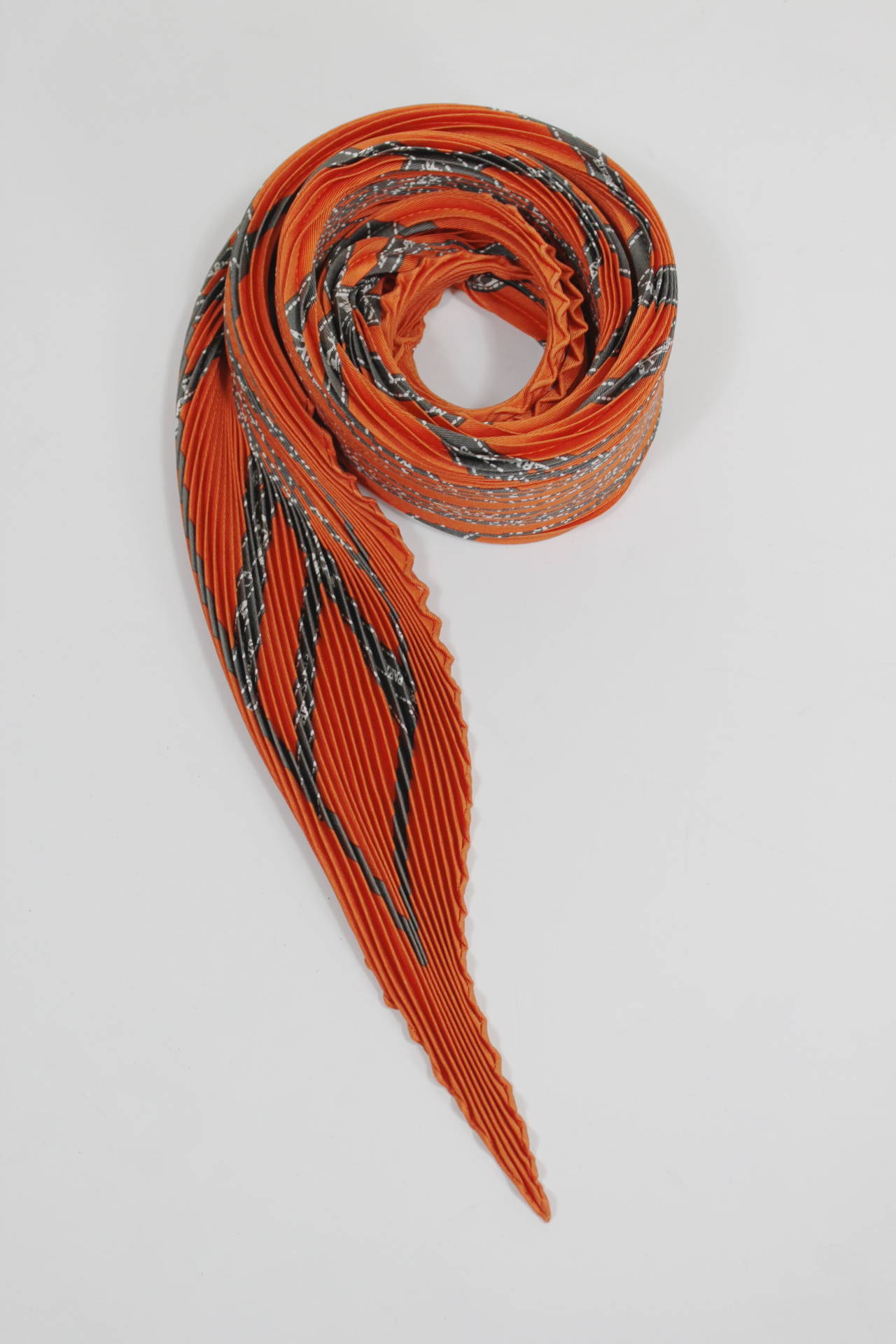 A classic plisse scarf from Hermès featuring the legendary brand's iconic orange and brown ribbon print. The scarf still has its original box.

Measurements--
50.5 inches from point to point