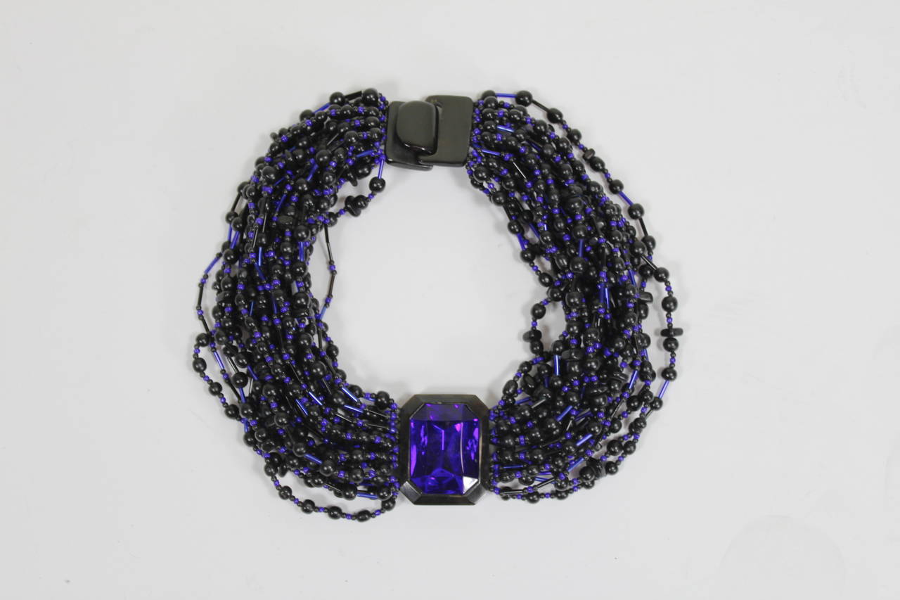 A fabulous necklace from Denmark's lauded Monies jewelry. The collar necklace is made up of 26 strands of striking blue glass beads alternating with dark disc and round wooden beads. The central pendant is also a gorgeous striking blue set in