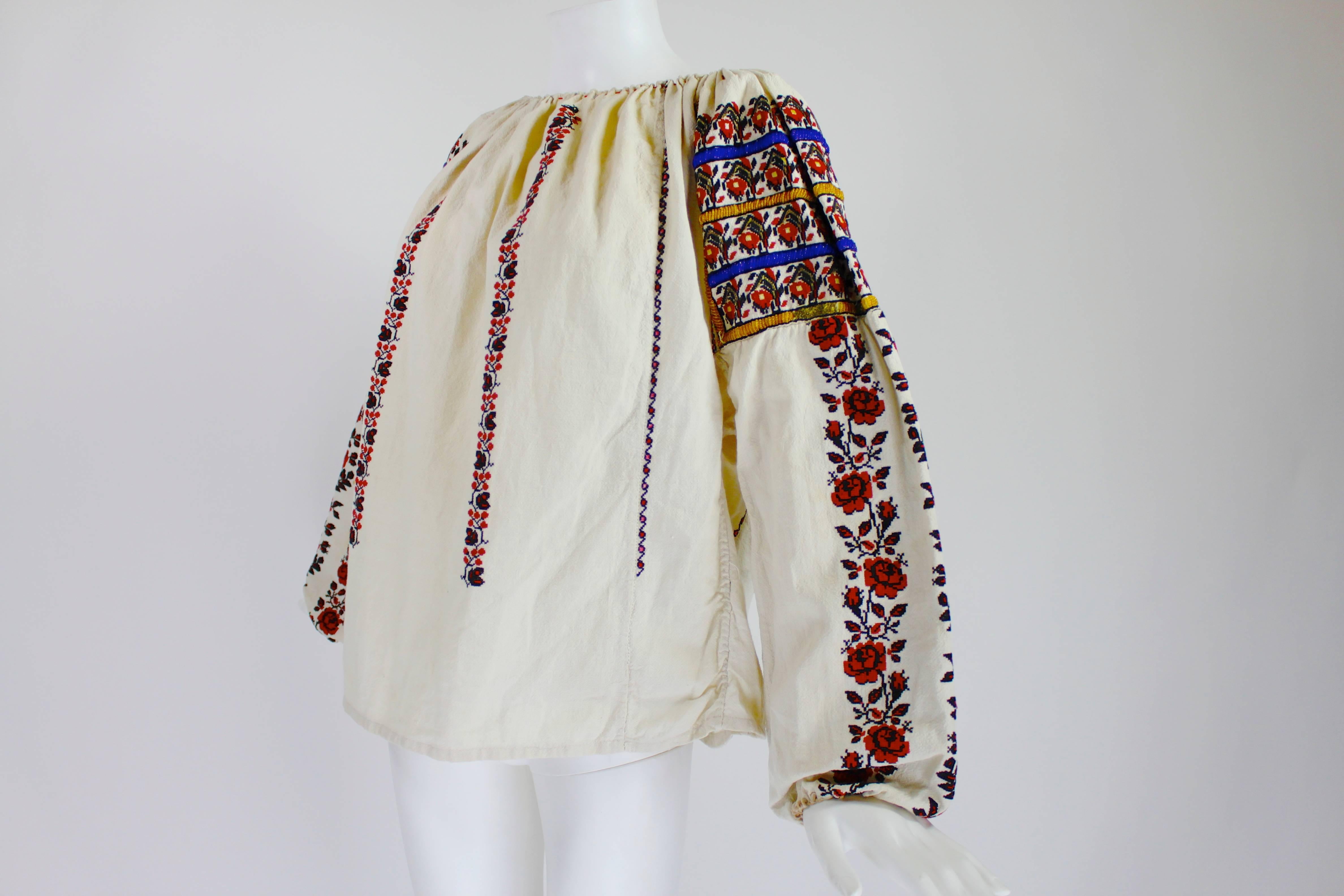 This is one of the best late 1920s/early 1930s Eastern European embroidered peasant blouses we've seen! The blouse is covered with vines of bright red rose embroidery and the shoulders are capped with alternating blue and yellow stripes of beadwork.