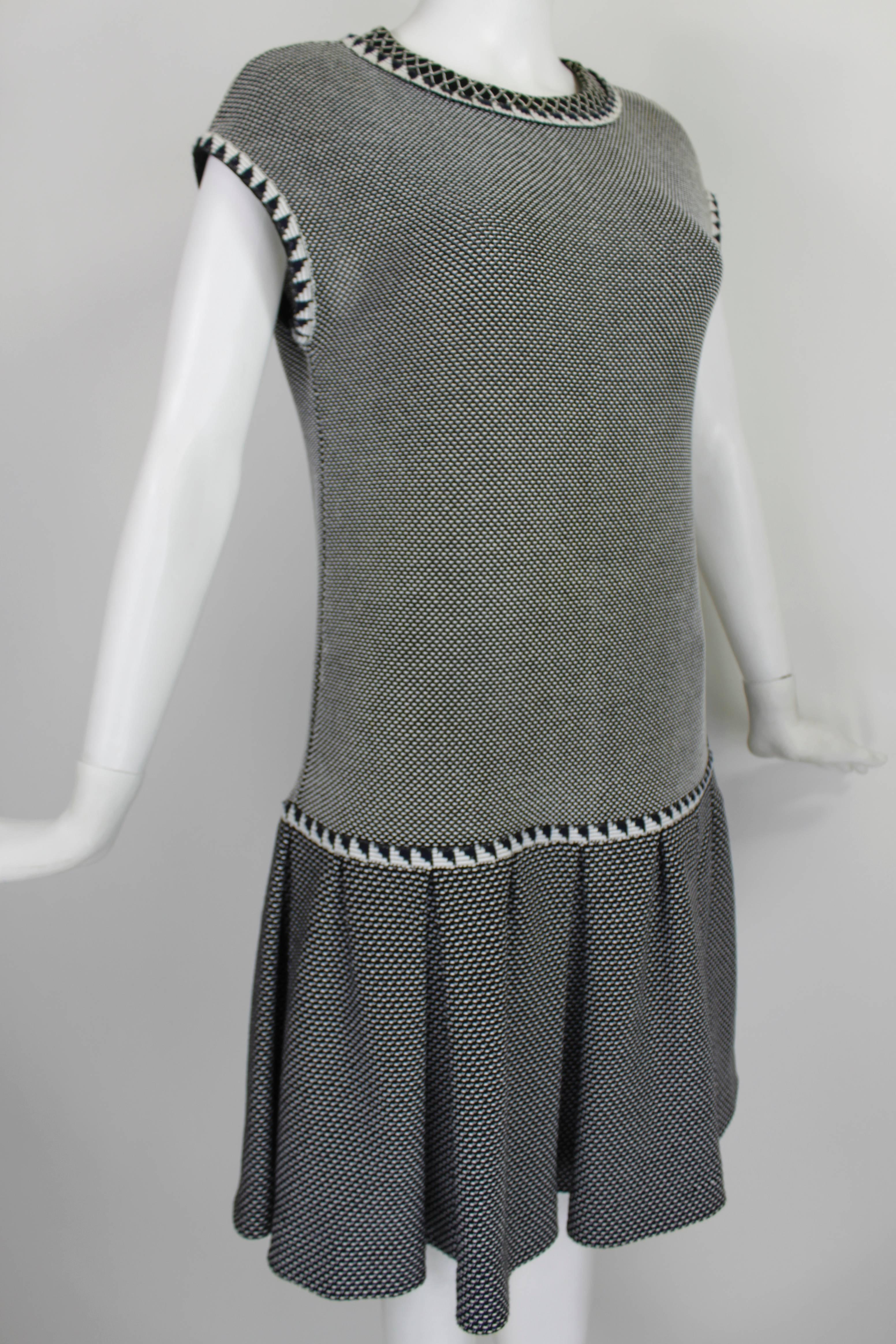This fabulous knit dress from Chanel features a fine contrasting graphic op-art pattern. The trim around the neck, arm holes, and waistband have a black and white back-to-back triangle print, as well as intricately wrapped piping with dots of navy