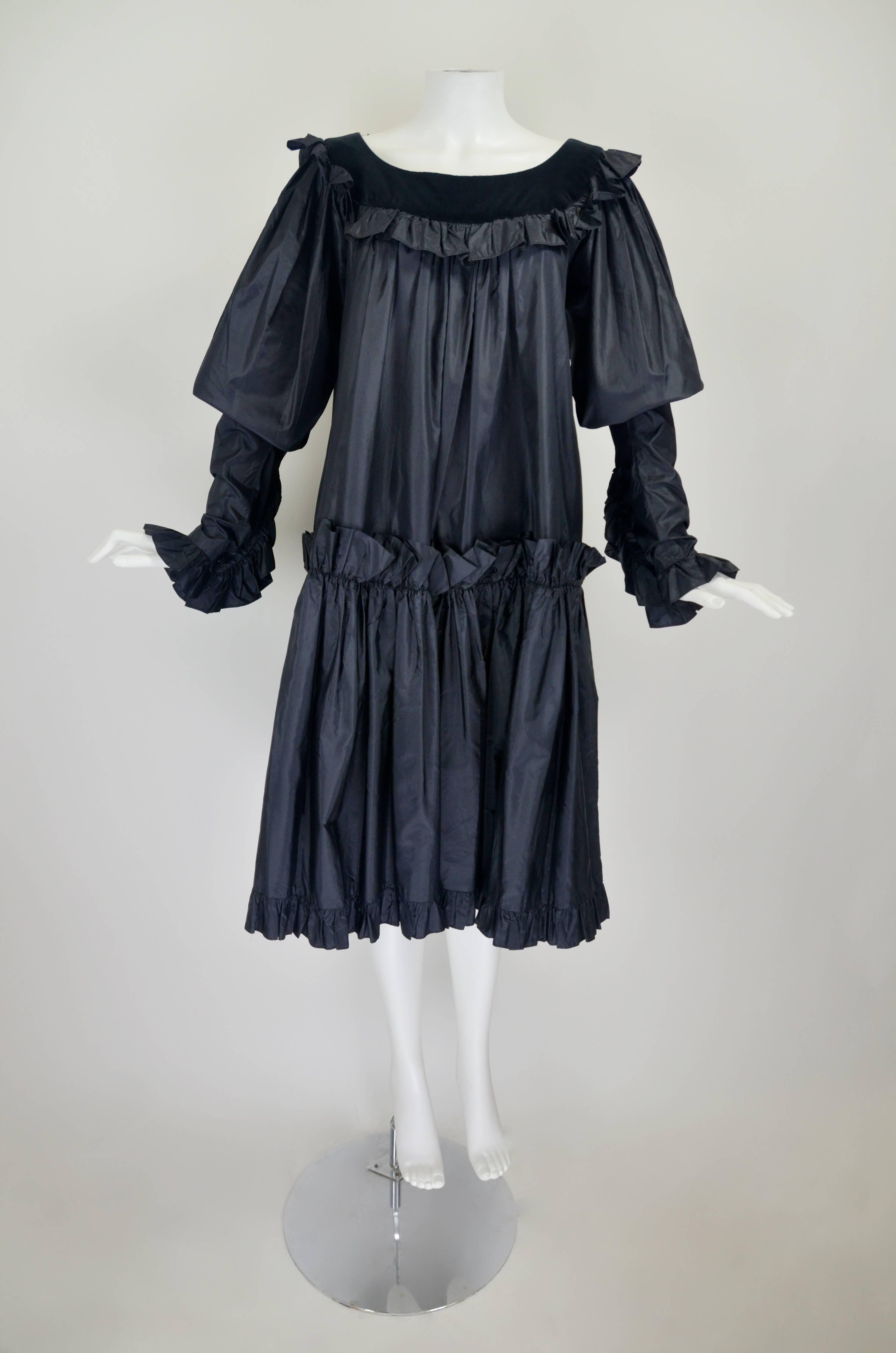 This is a fabulous peasant dress from YSL Rive Gauche. The fashion house's iconic peasant silhouette is done in chic black silk taffeta with a slight sheen. Ruffles trim the tapered sleeves as well as drop waist hem. Beveled black buttons adorn the