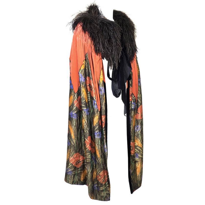 Twenties evening cape. Orange silk velvet with gold lamé in wheat & poppy print. Trimmed in black ostrich. Ties at neck. Excellent condition. 

Length:  44
