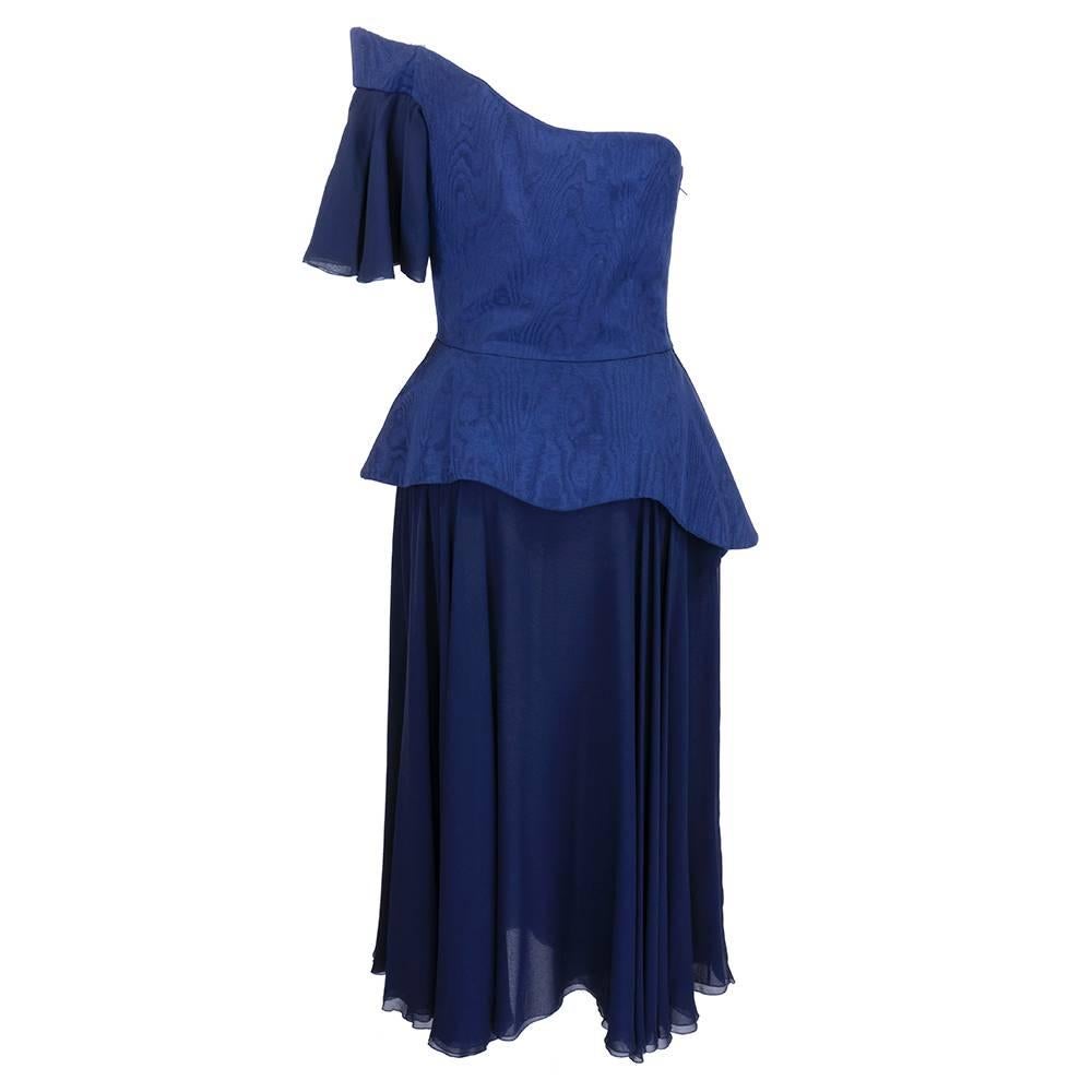 Deep blue moire and chiffon dramatic one shoulder cocktail dress with asymmetrical peplum, full skirt and draped cap sleeve. Super stunning silhouette with great movement. Boned corset topped with zip closure.