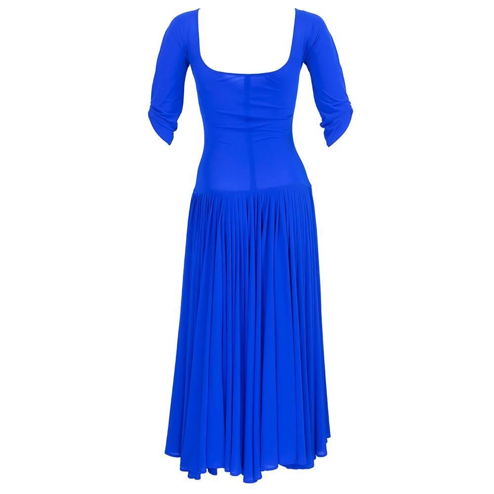 1990s dress by designer Norma Kamali in royal blue jersey. Wonderful stretch fabric with drop waisted cut and extra full pleated mid-length skirt. Sexy scoop neck with shirred bust and three quarter sleeves.