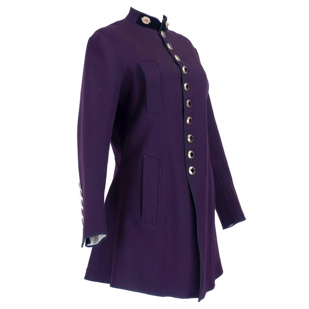 Military style coat  by Jean Paul Gaultier in eggplant colored 100% wool. Gold braided accents on black velvet collar. Slash pockets  and stylish brass buttons down front, back vent and cuffs. Fully lined.   Pleated from waist down in rear - very