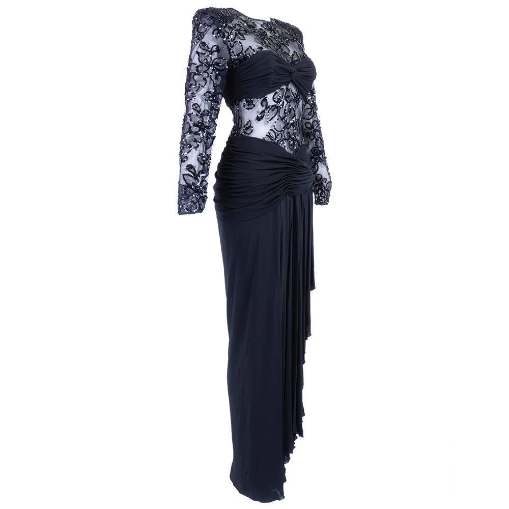 1980s evening gown by Vicky Tiel in black jersey with  sheer peek-a-boo net panels with decorative sequins in a floral motif.Very 1980s does 1940s. Shirred bra top panel with shirring and swag at waist- boned at hip. Sheer back. Super sexy. Zips up