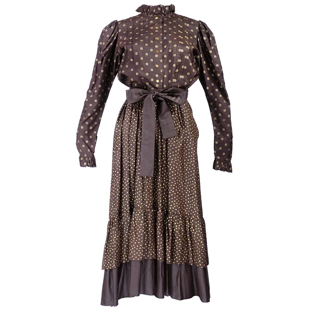 YSL's famous peasant silhouette in brown and gold. Two piece ensemble of ruffled cuff and collar blouse with snap front closure paired with tiered peasant skirt with sash belt.