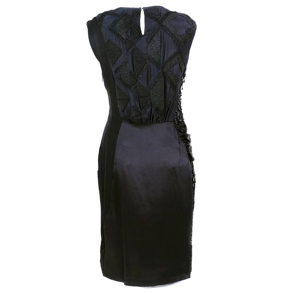 1990s simple and elegant evening dress by noted Belgian designer Dries Van Noten. Black satin sheath heavily embelished with black beads and asymmetrical sash at waist. Wonderful avant garde styling.