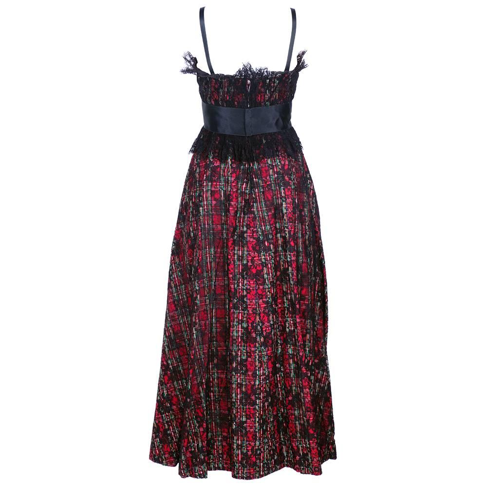 1970s Geoffrey Beene Boutique red and green plaid gown overlaid with black lace. Gathered bodice with empire waist and Satin bow. Fully lined with full skirt.