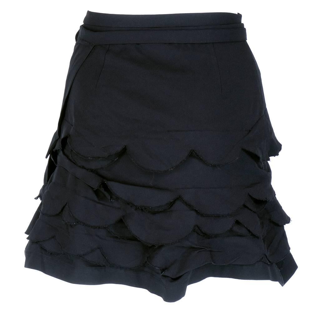 Comme des Garcons Wrap skirt in black polyester blend fabric with slight stretch. Tagged size medium but sizing flexible due to wrap style. Asymmetrical scalloped edged tiers. Horizontal strips of fabric irregularly stitch with unfinished edges,